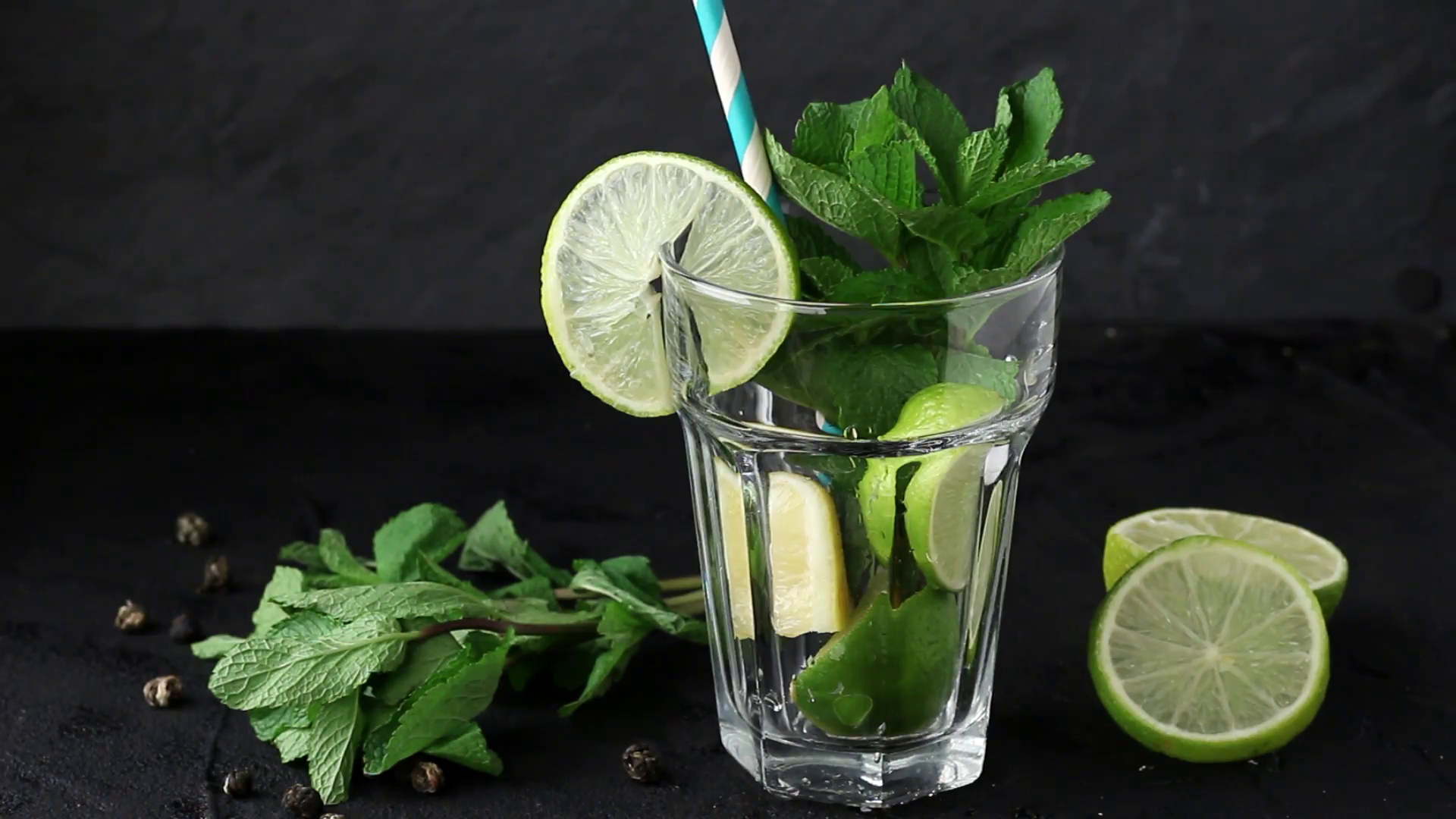 Pouring in glass Iced green tea with lime, lemon and mint on black ...