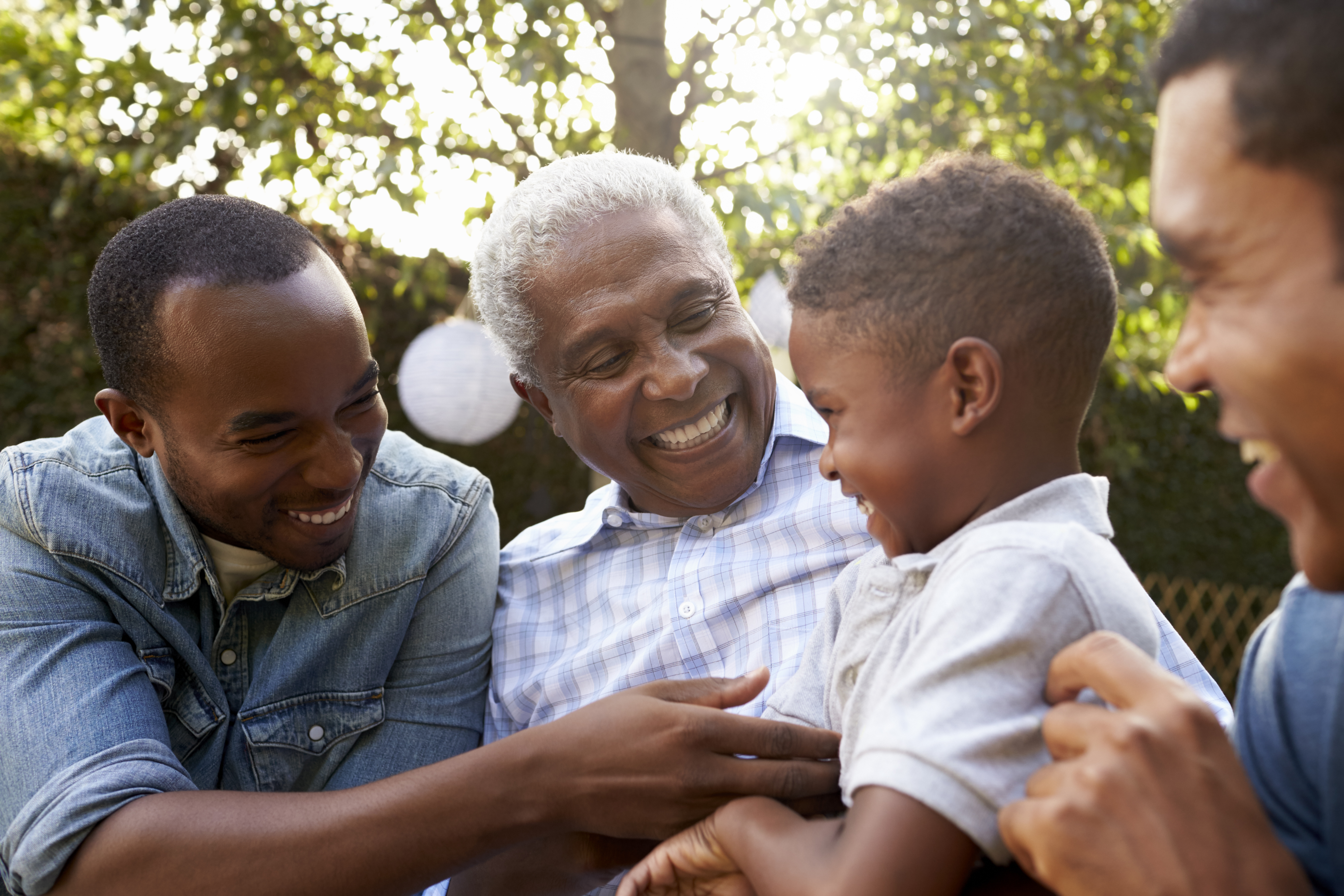 Black grandfather, sons and grandson talking in a garden – Henry STL