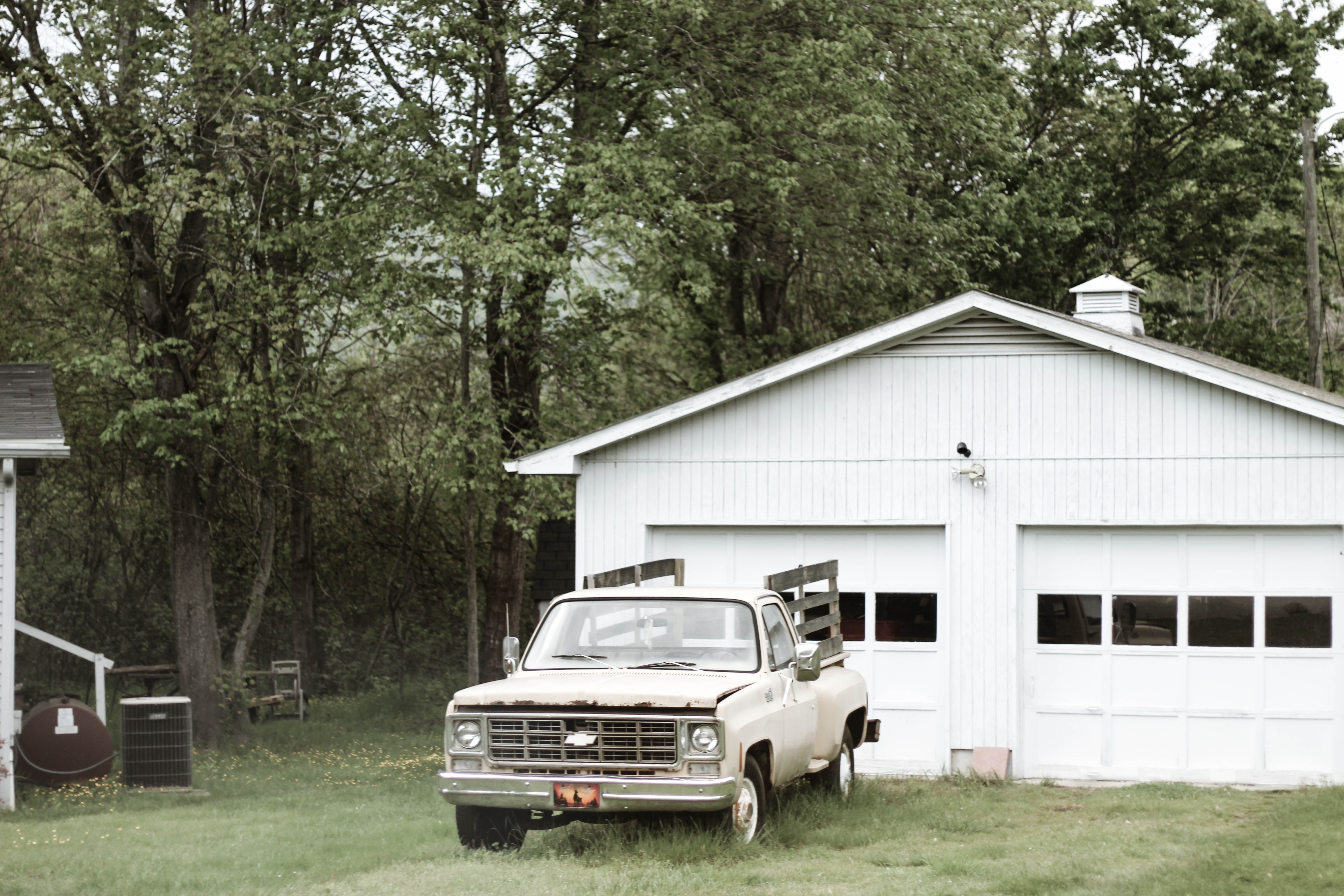 Gray chevrolet car parked near white shed photo