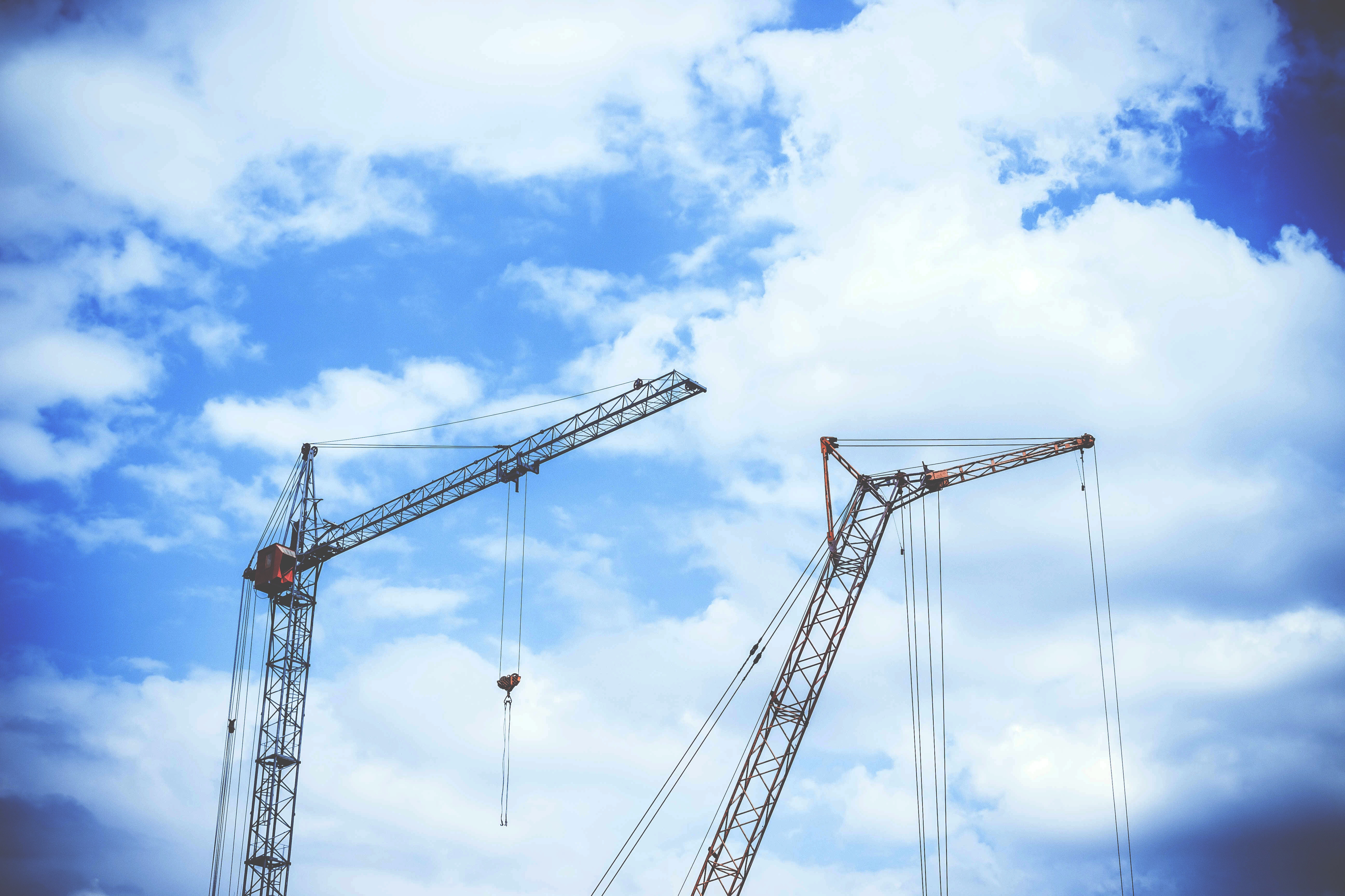 Gray rectangular power crane with blue cumulus clouds above as background during daytime photo