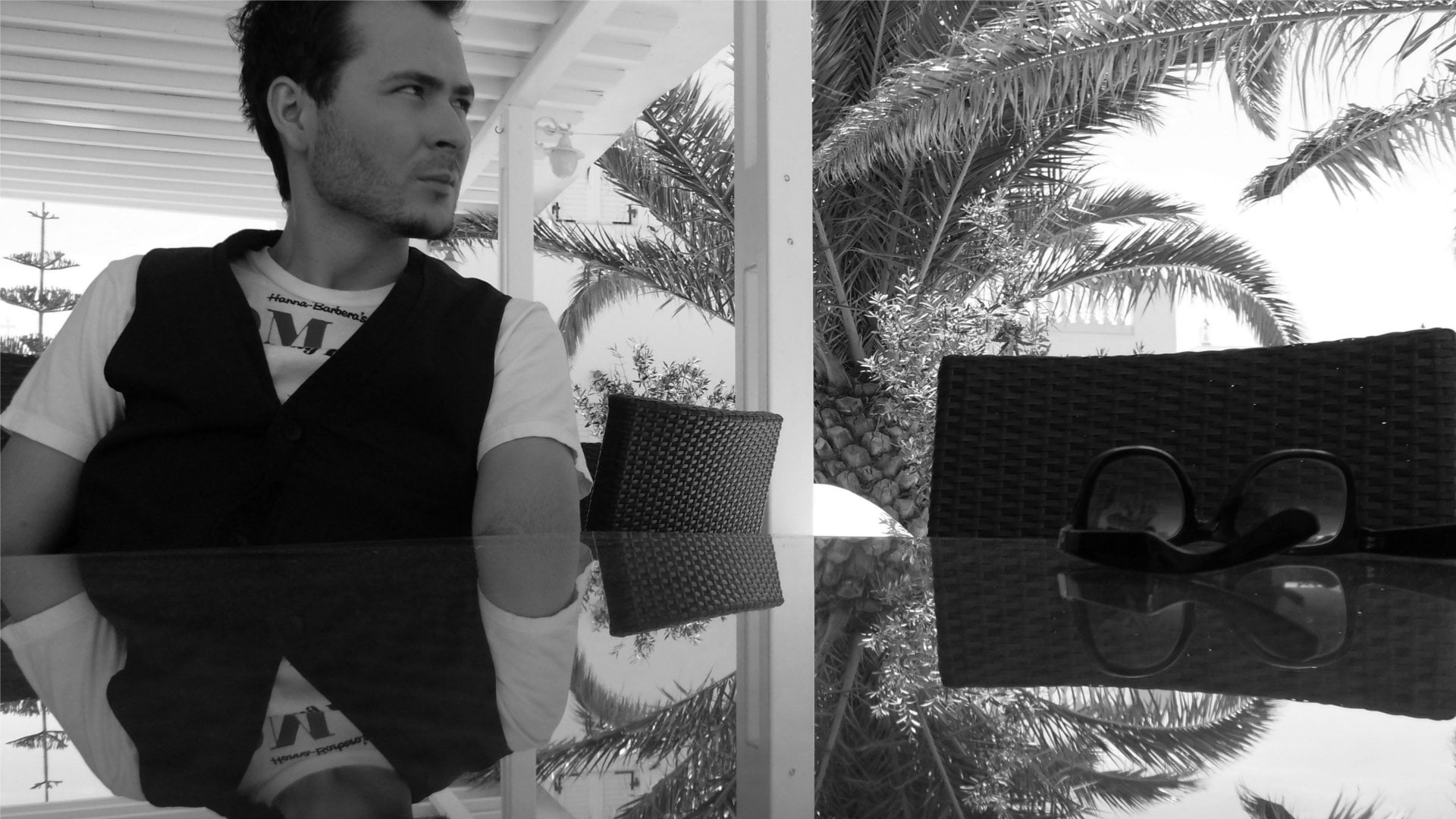 Grayscale photo of man in shirt and vest sitting in front of glass ...