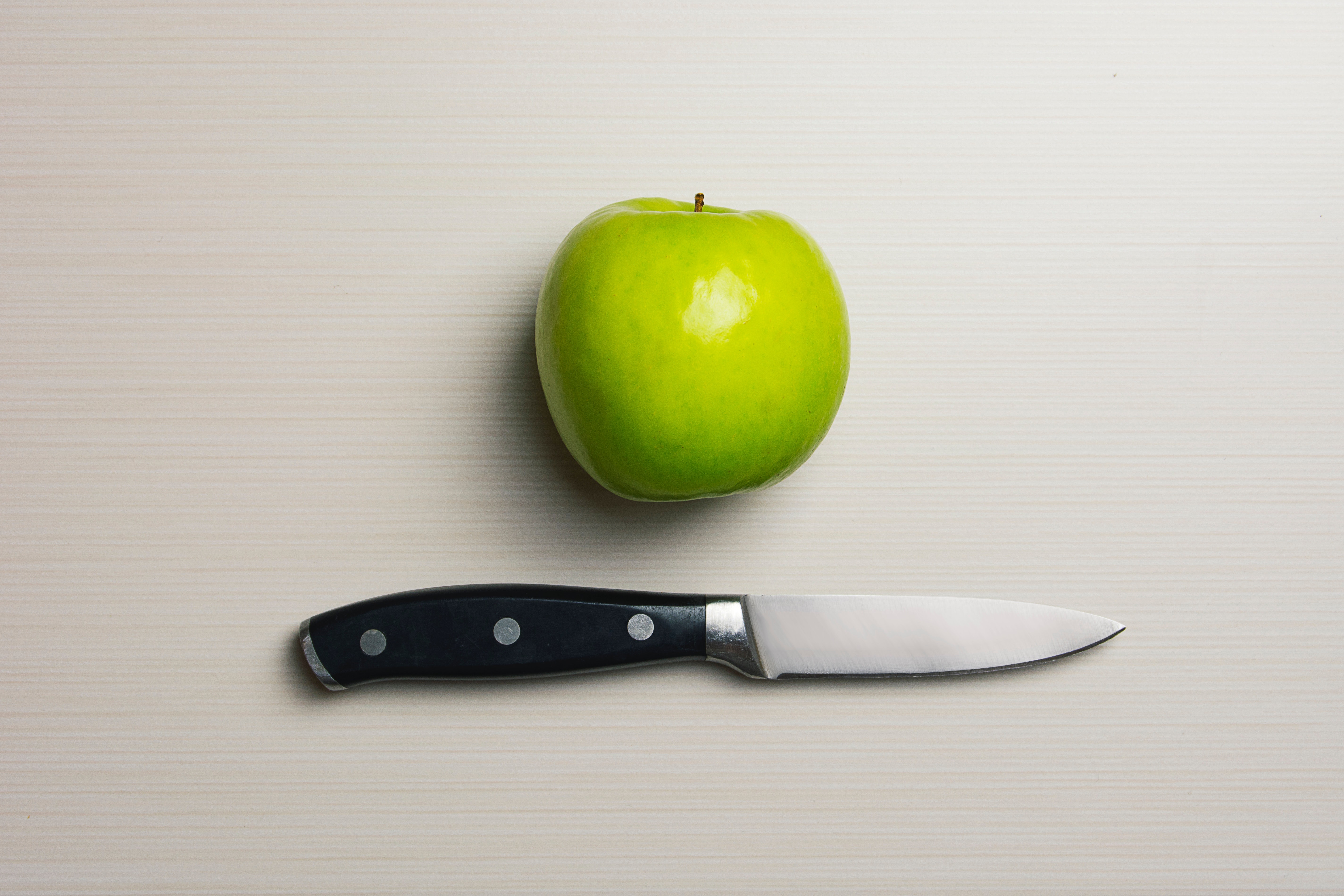 Green apple beside silver bladed knife photo