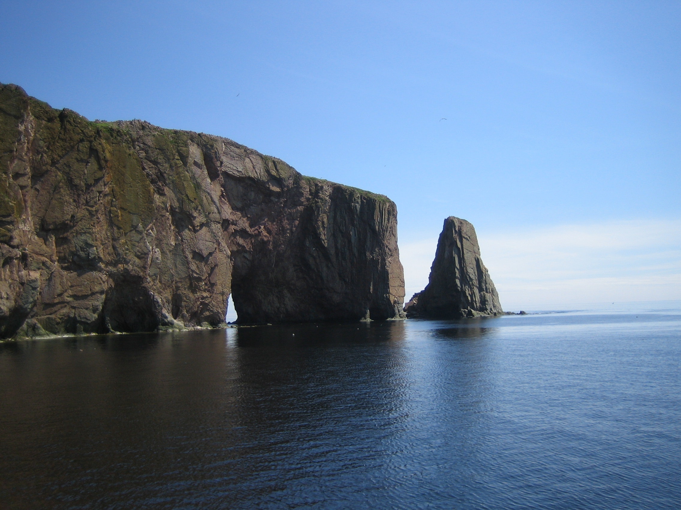 Grey cliff on blue calm sea during daytime photo