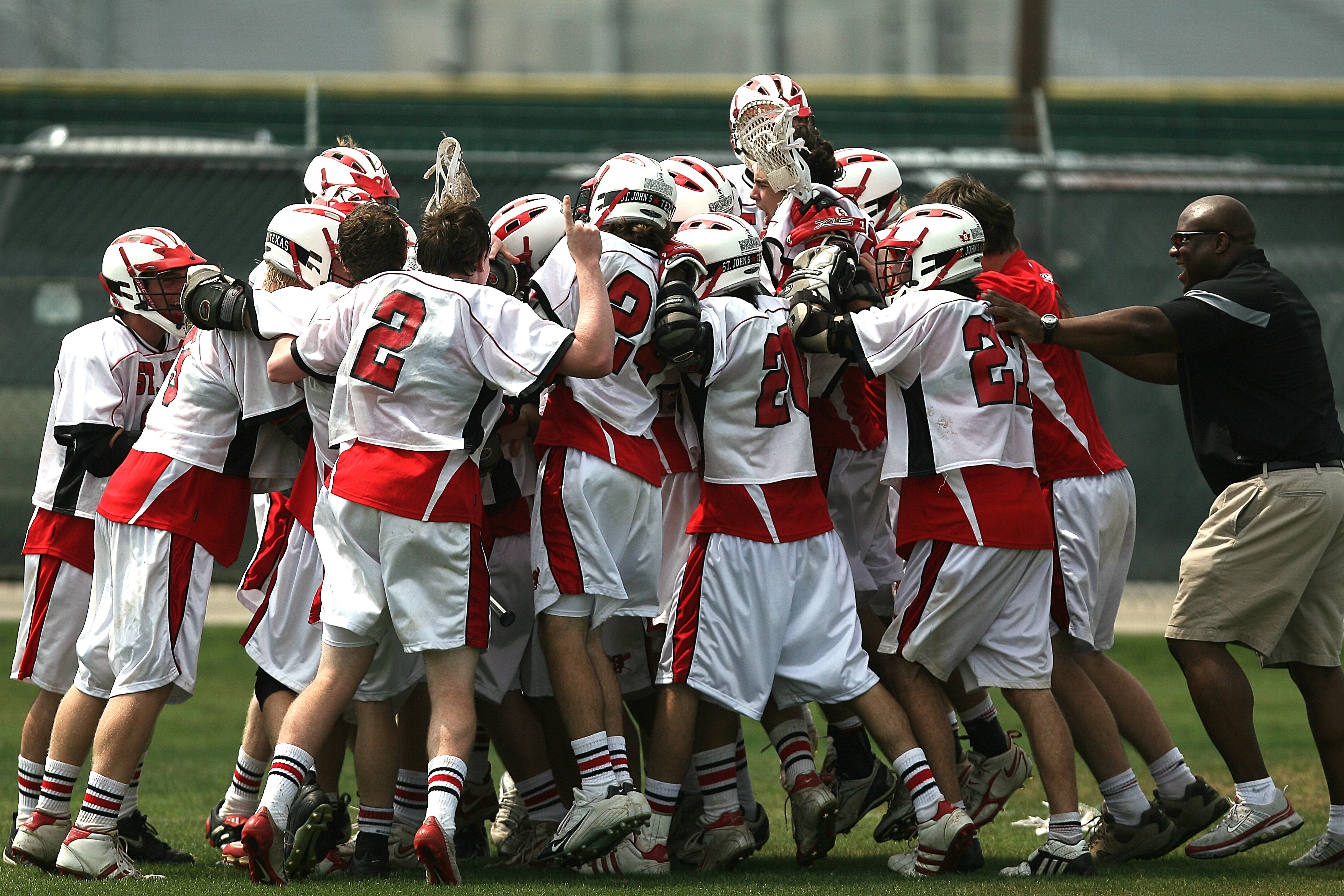 Group of lacrosse players celebrating with coach during daytime photo