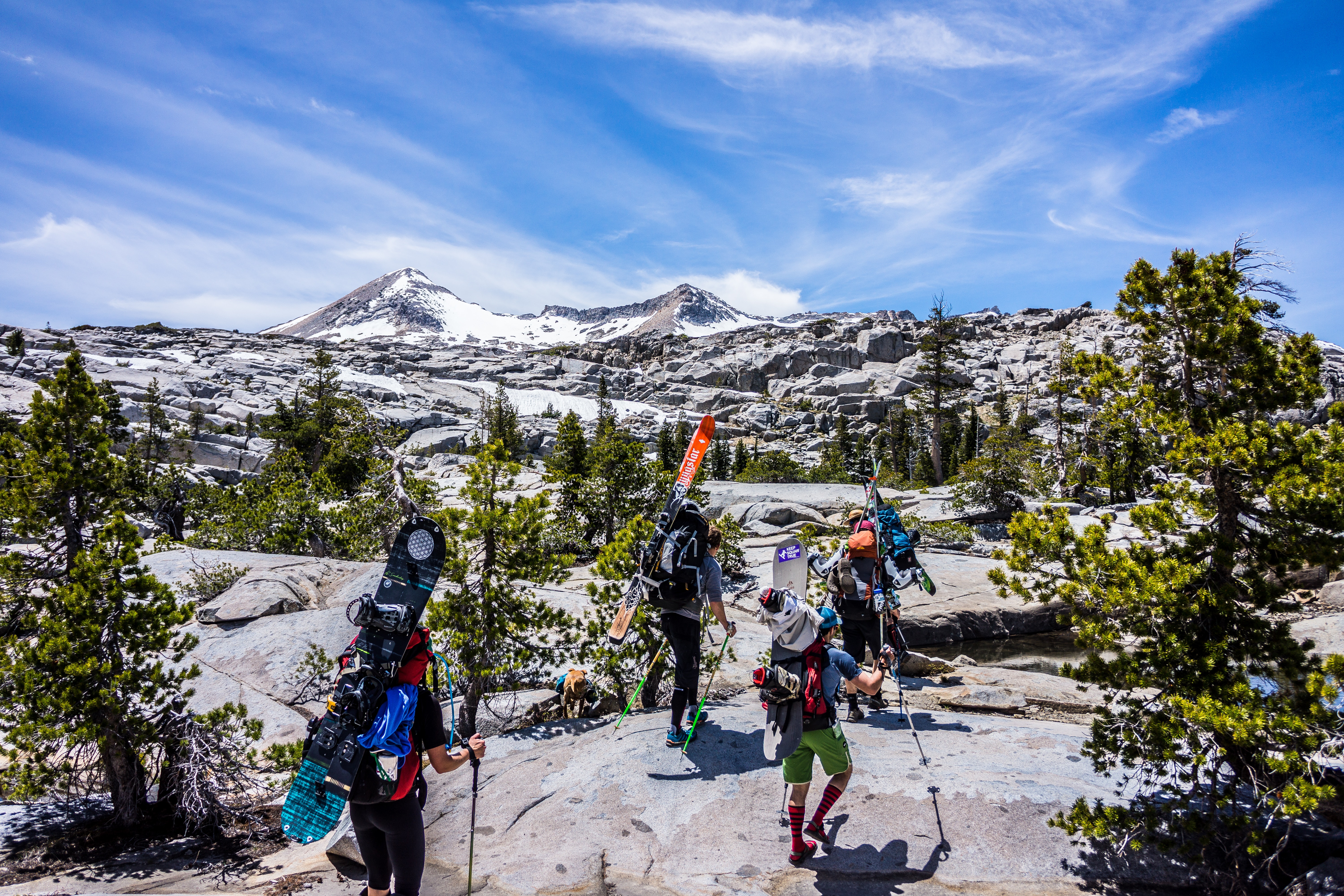 Group of people hiking with snowboards under blue cloudy sky photo