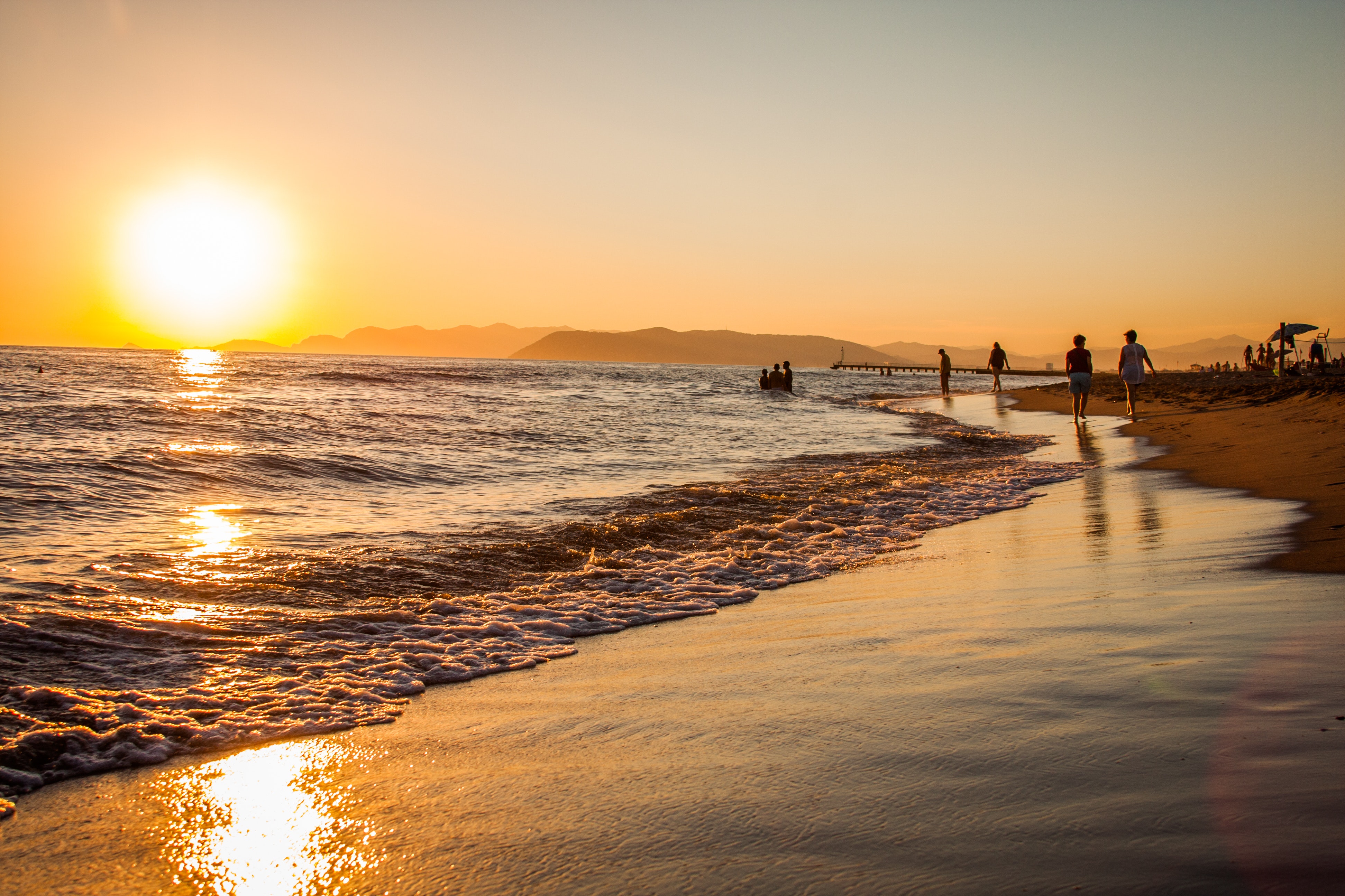 Group of people walking at the shoreline during golden hour photo