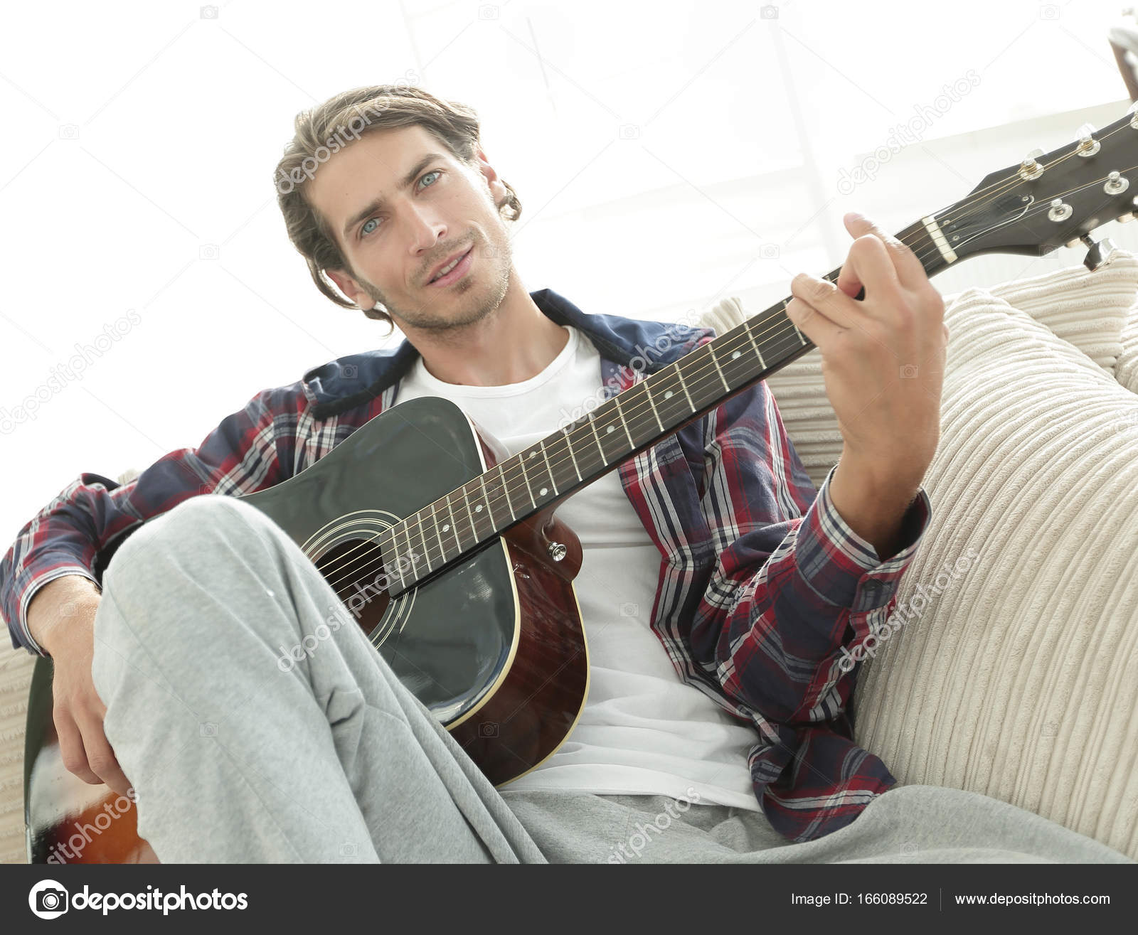 modern guy with guitar sitting on sofa in living room. — Stock Photo ...
