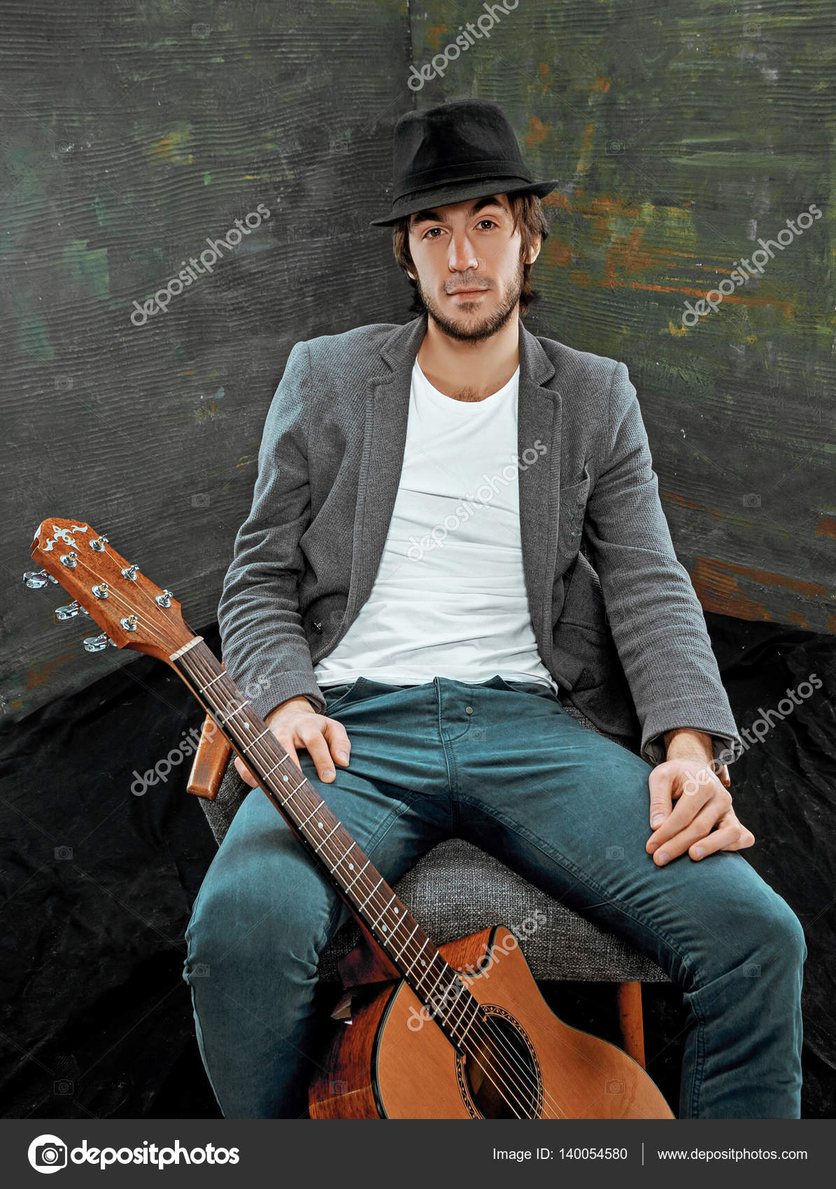 Cool guy sitting with guitar on gray background — Stock Photo ...