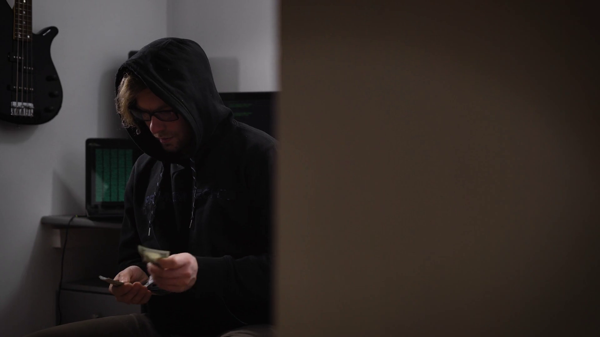 A hacker in the computer room. A man in a jacket with a hood ...