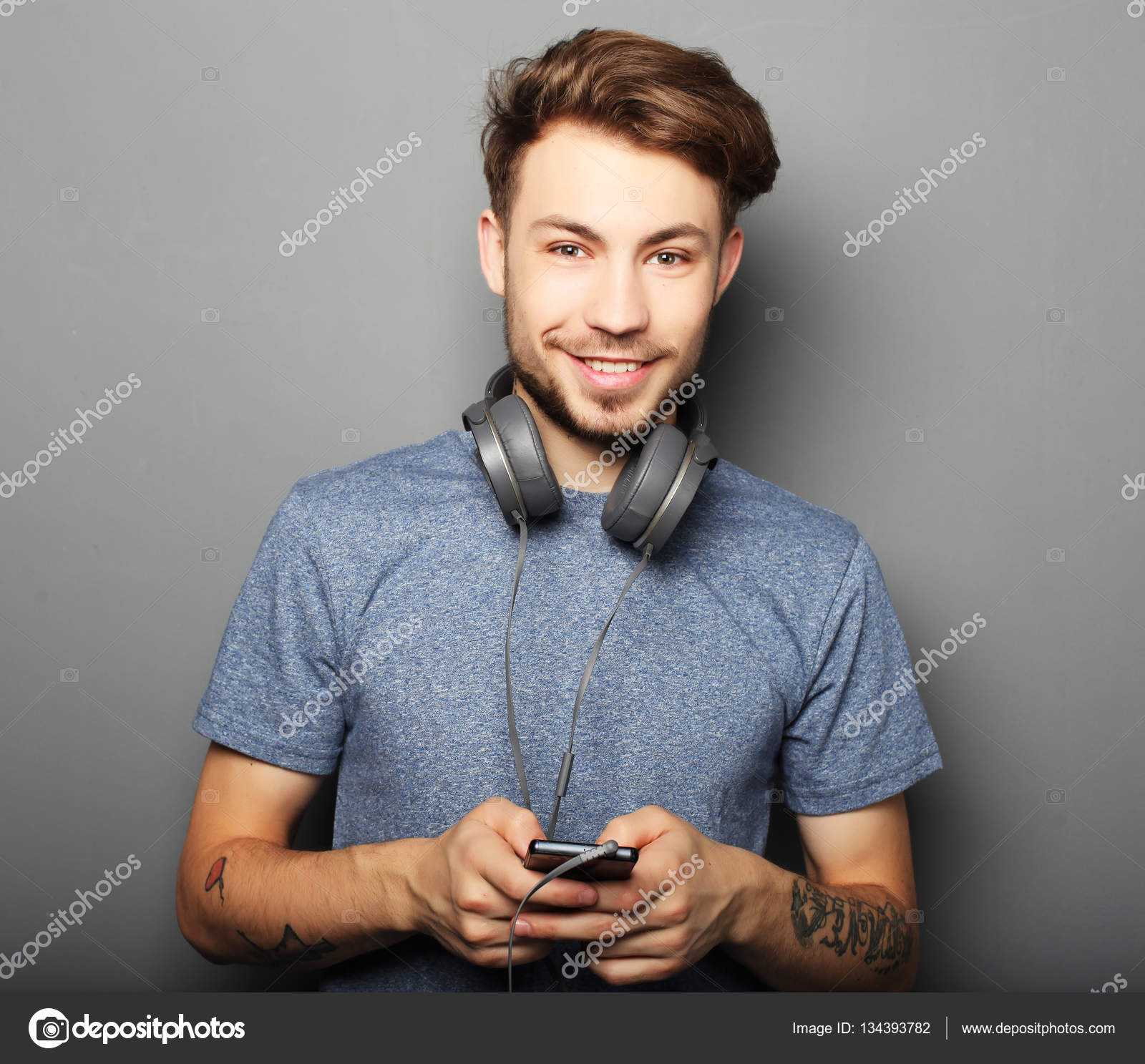Handsome young man wearing headphones on his neck and smiling wh ...