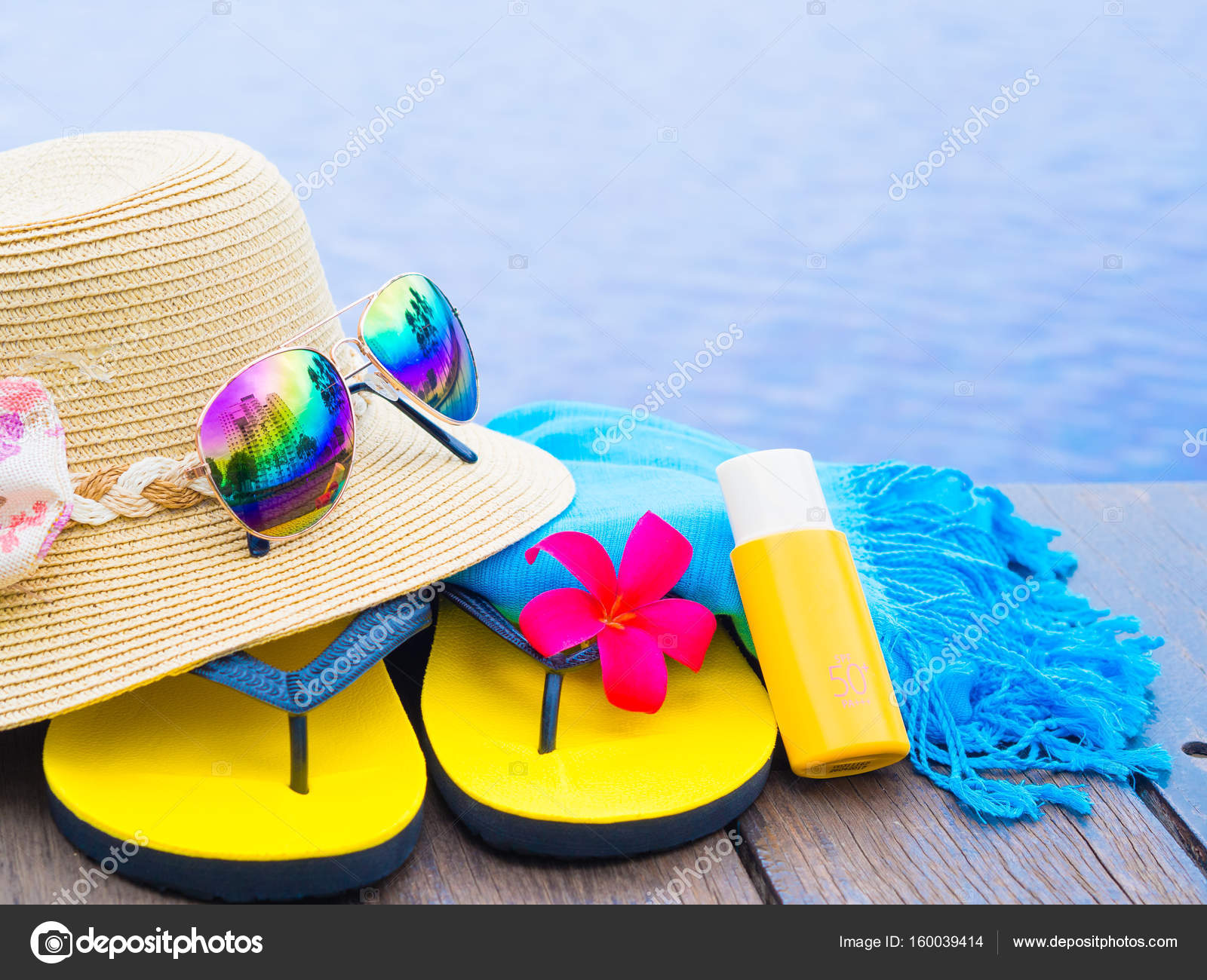 Sunglasses with summer hat, flip flops, sunscreen lotion and flowers ...