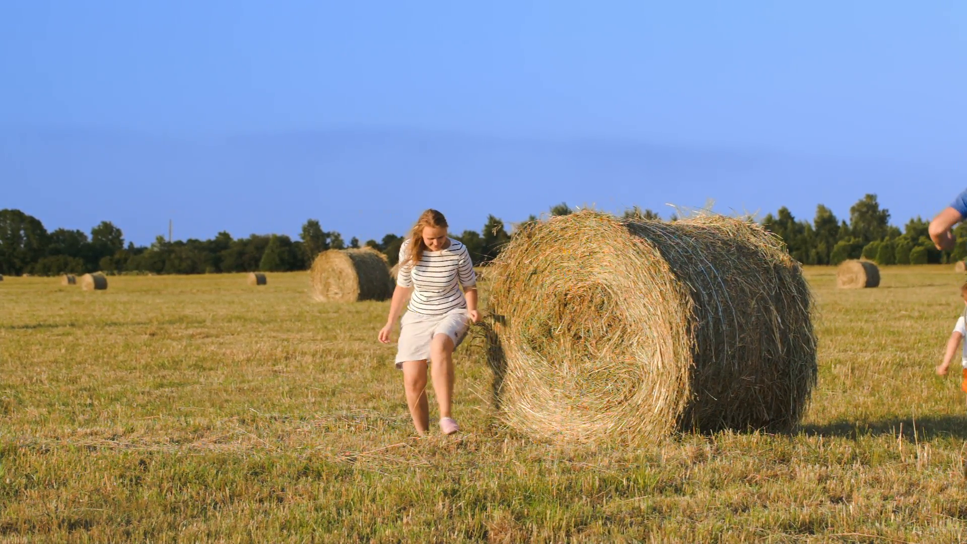 Young parents and son running and playing around the hay roll in the ...