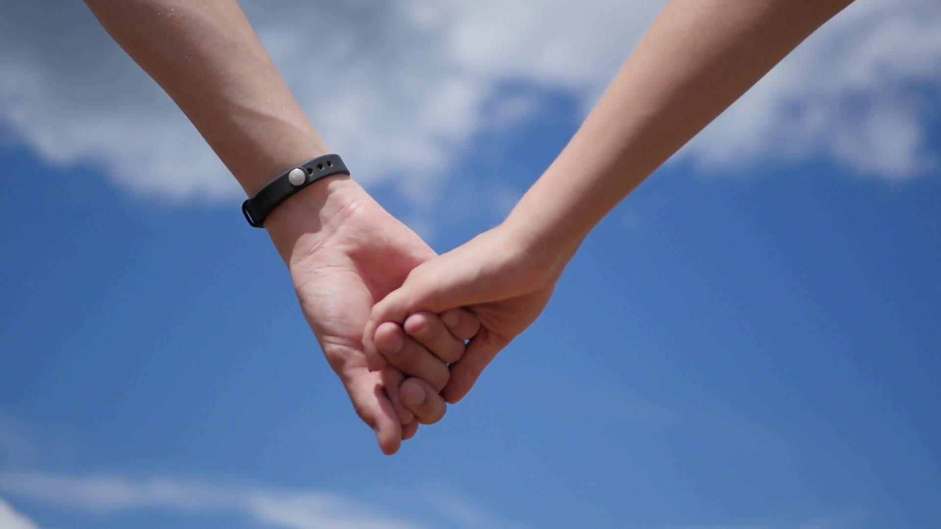 Hands of couple held together on the background of the blue sky ...