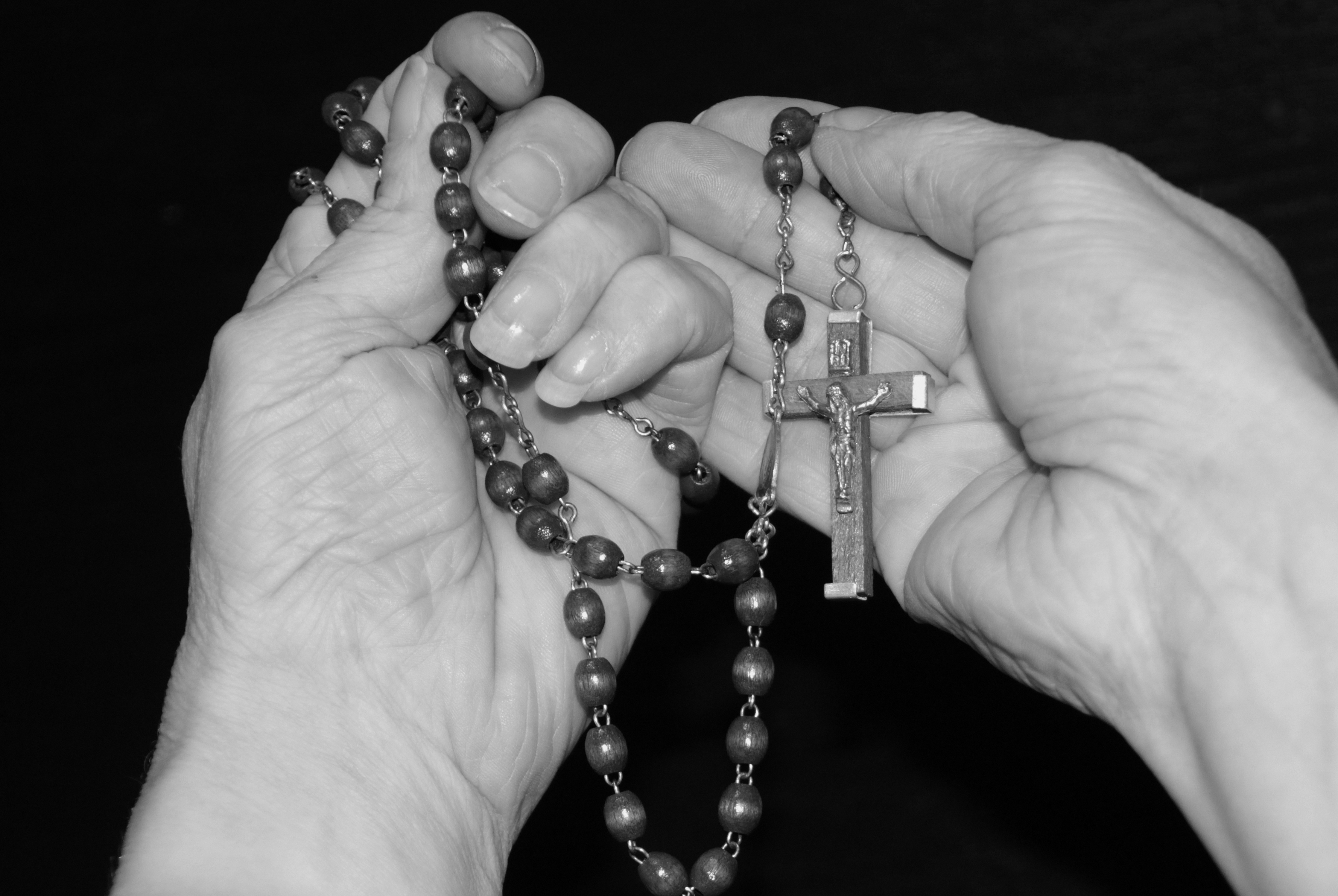 Holding a cross on string of beads - black & white photo