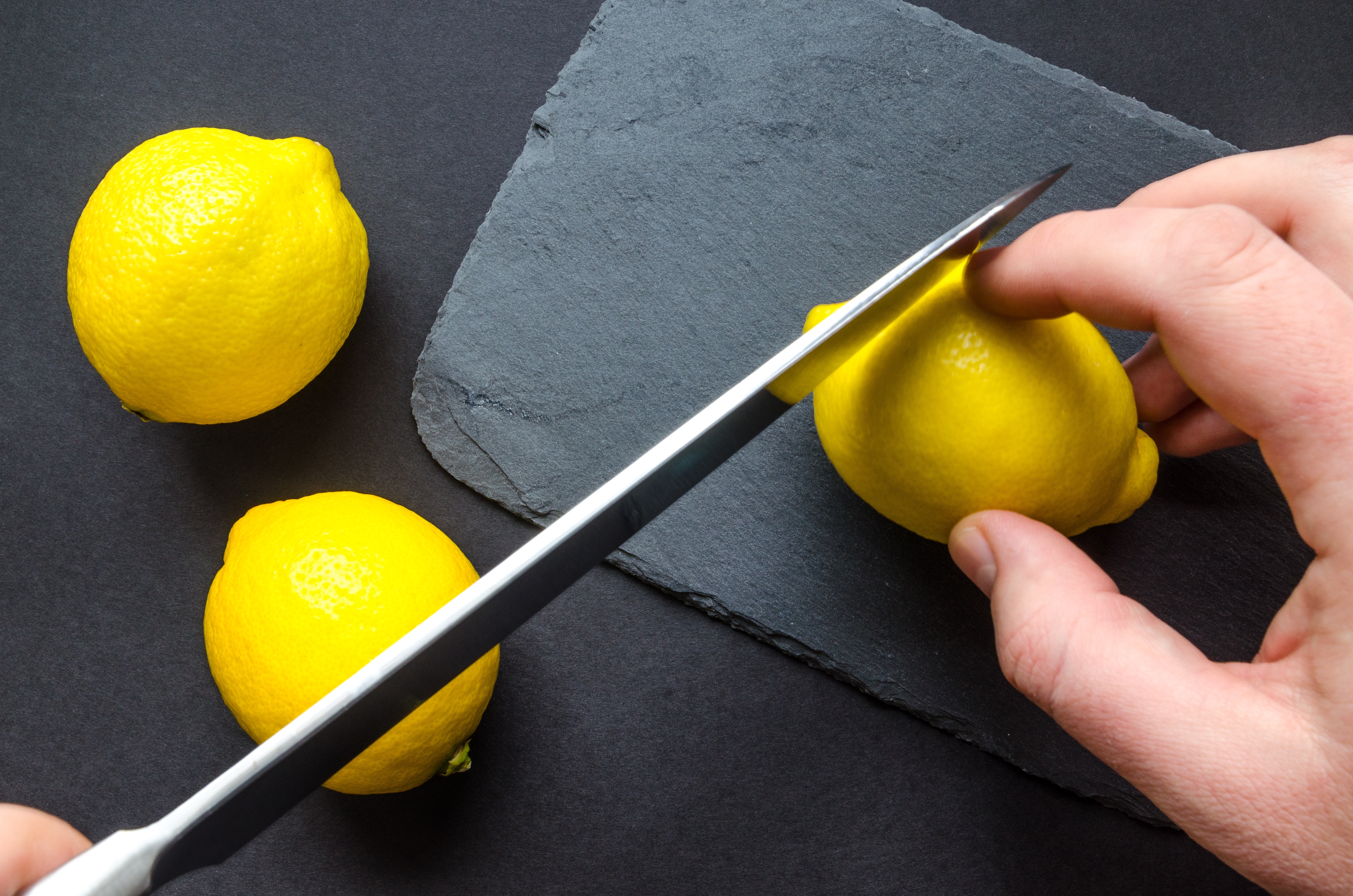 Human slicing yellow lemon photo