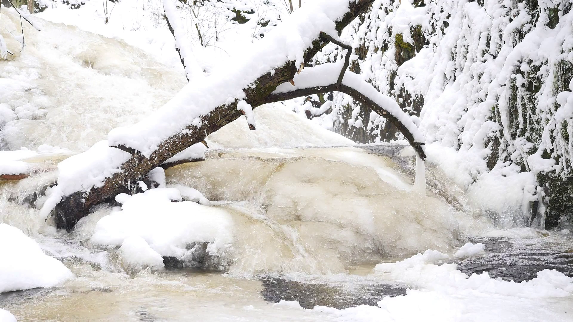 Frozen mountain stream. Snowy and icy stones in chilly water. Icicle ...