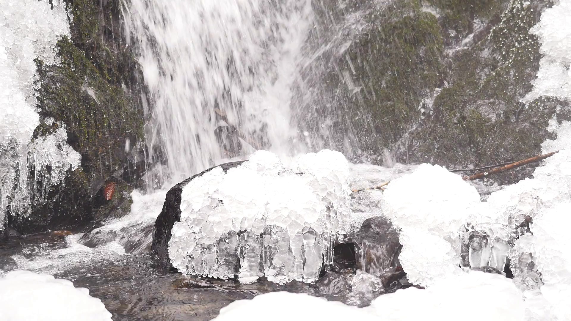 Iciciles bellow waterfall. Snowy and icy stones and boulders with ...