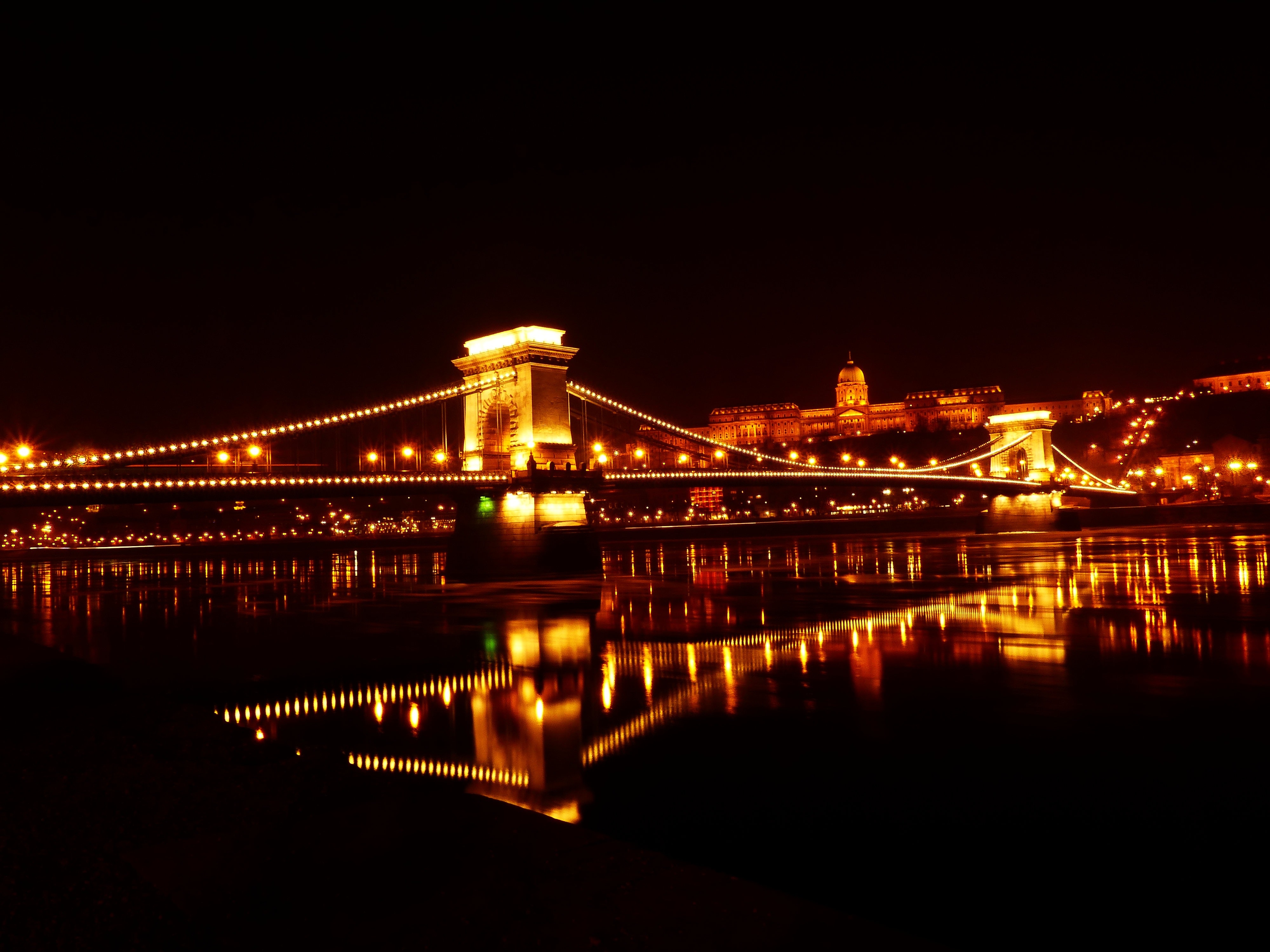 Illuminated bridge over river at night photo