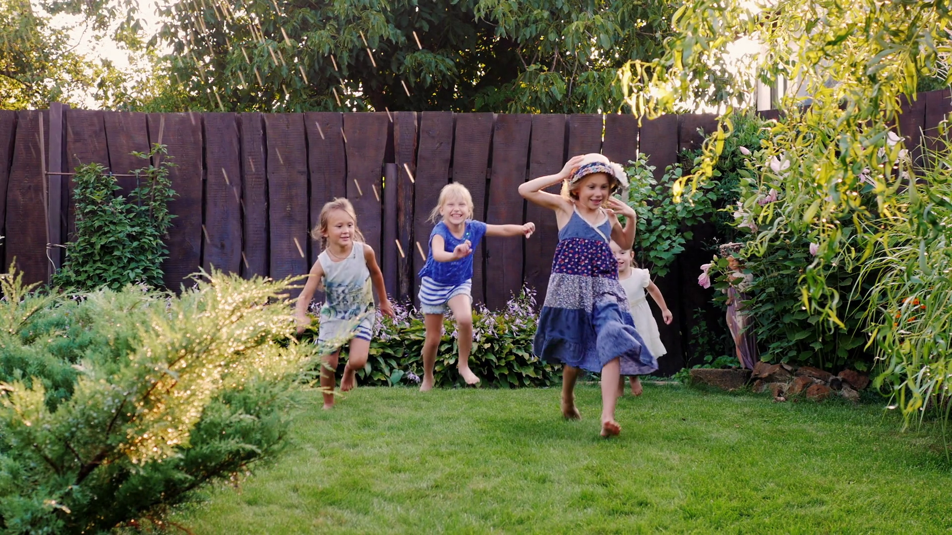 Carefree fun children play in the garden. Laughing, running under ...