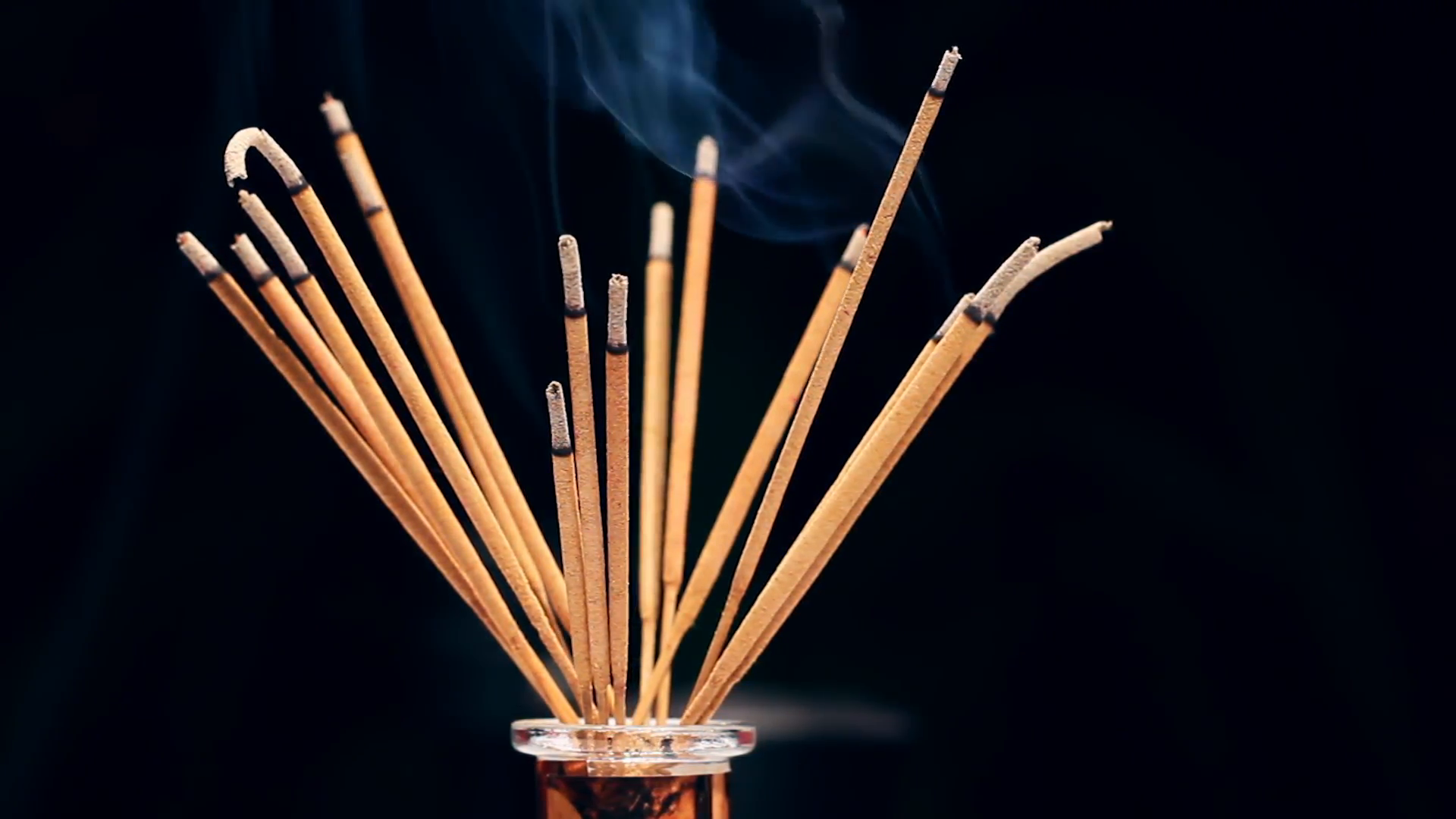 Close up of burning incense sticks with smoke over black background ...