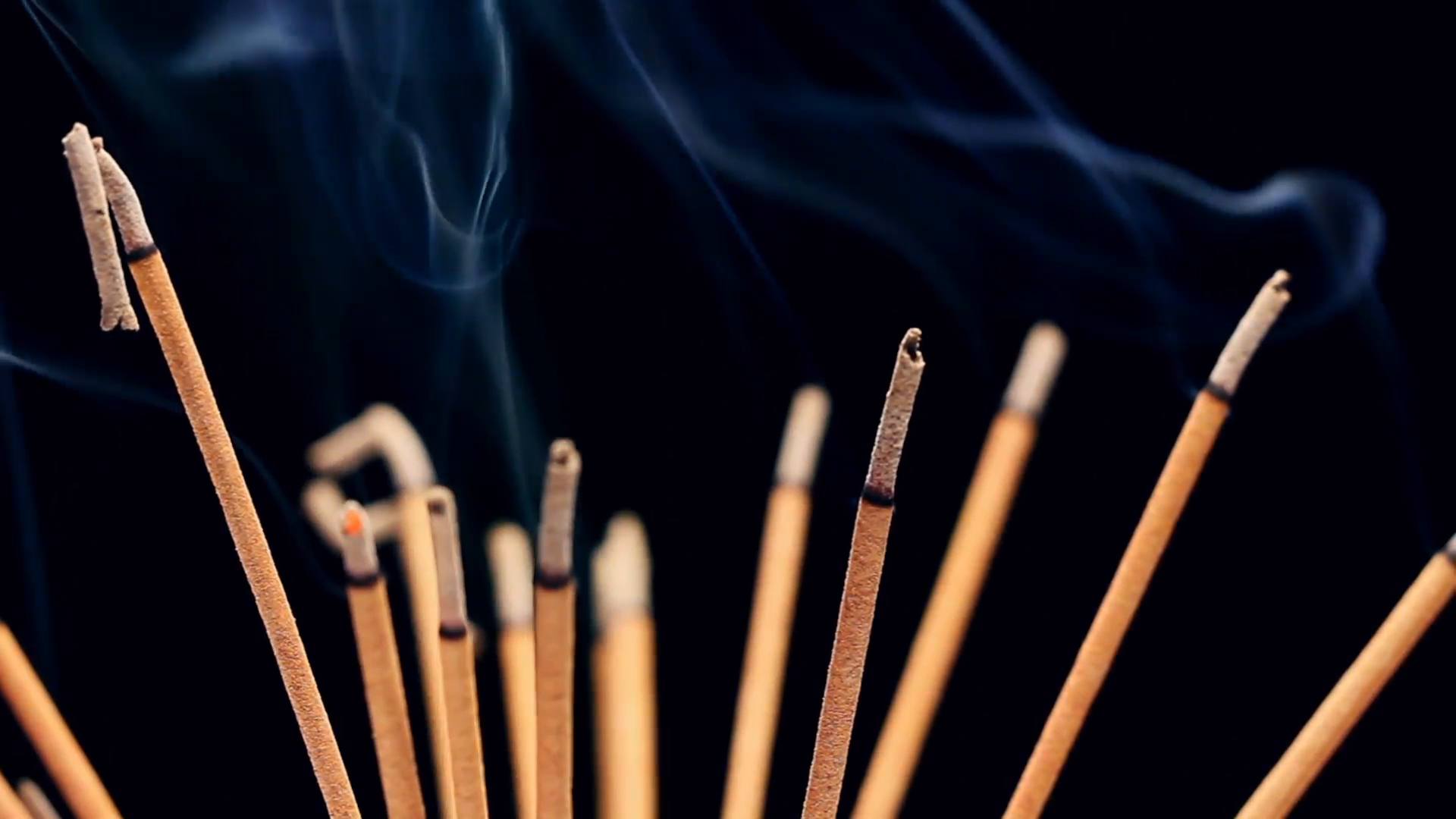 Close up of burning incense sticks with smoke over black background ...