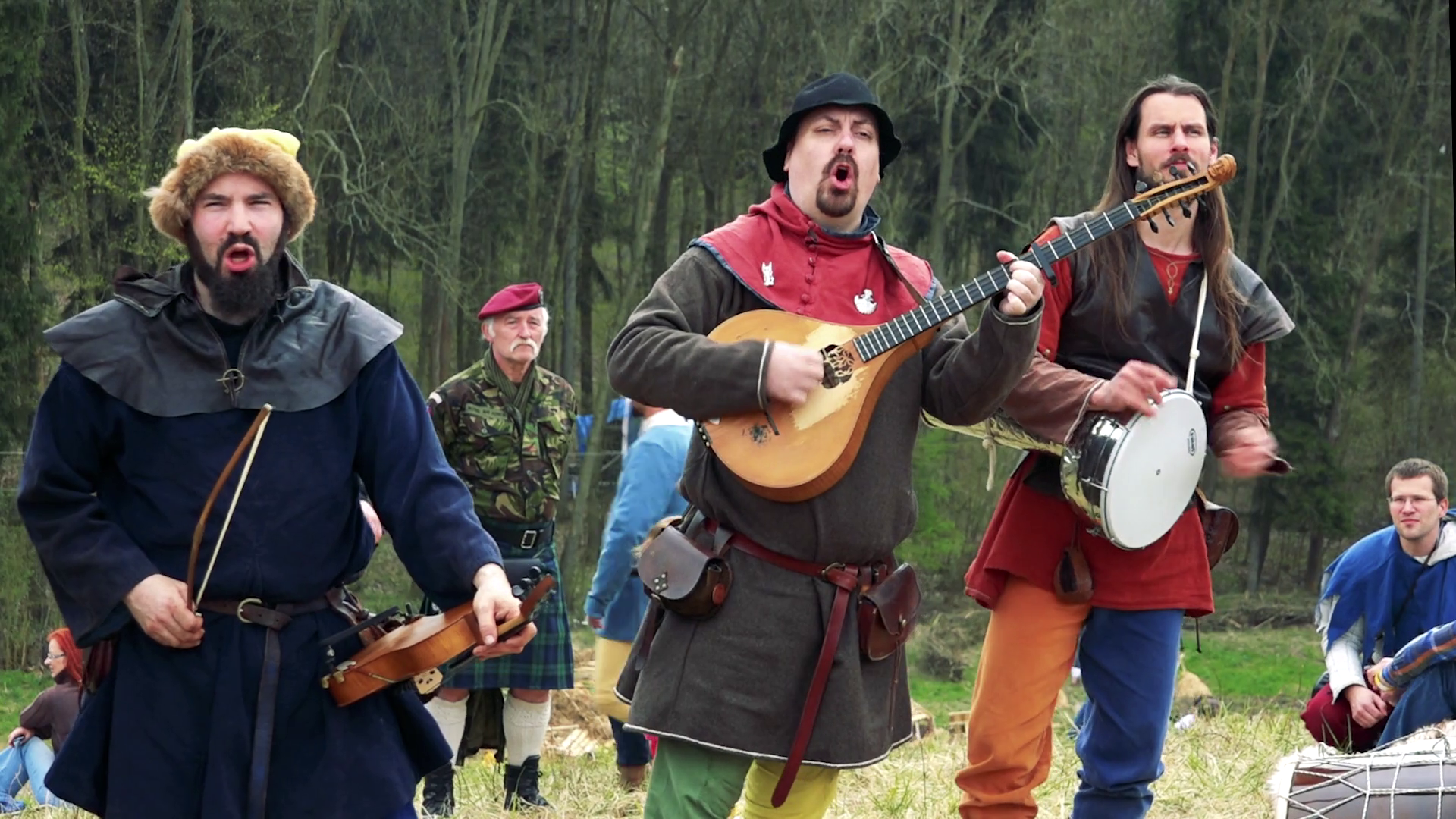 Three men in mediaeval costumes stand, sing and play on musical ...