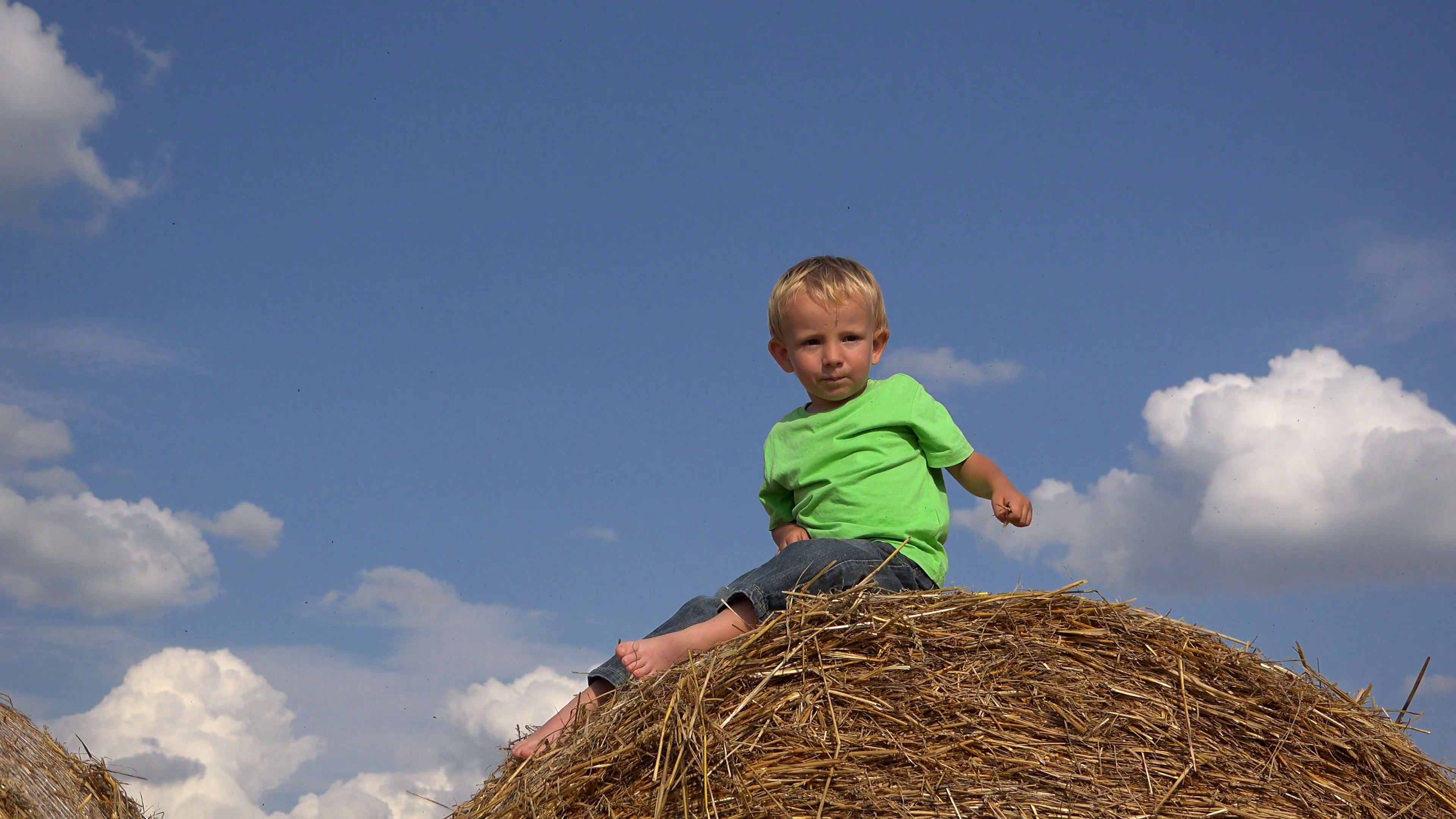 Joyful child on haystack top close blue sky trow off with straw ...