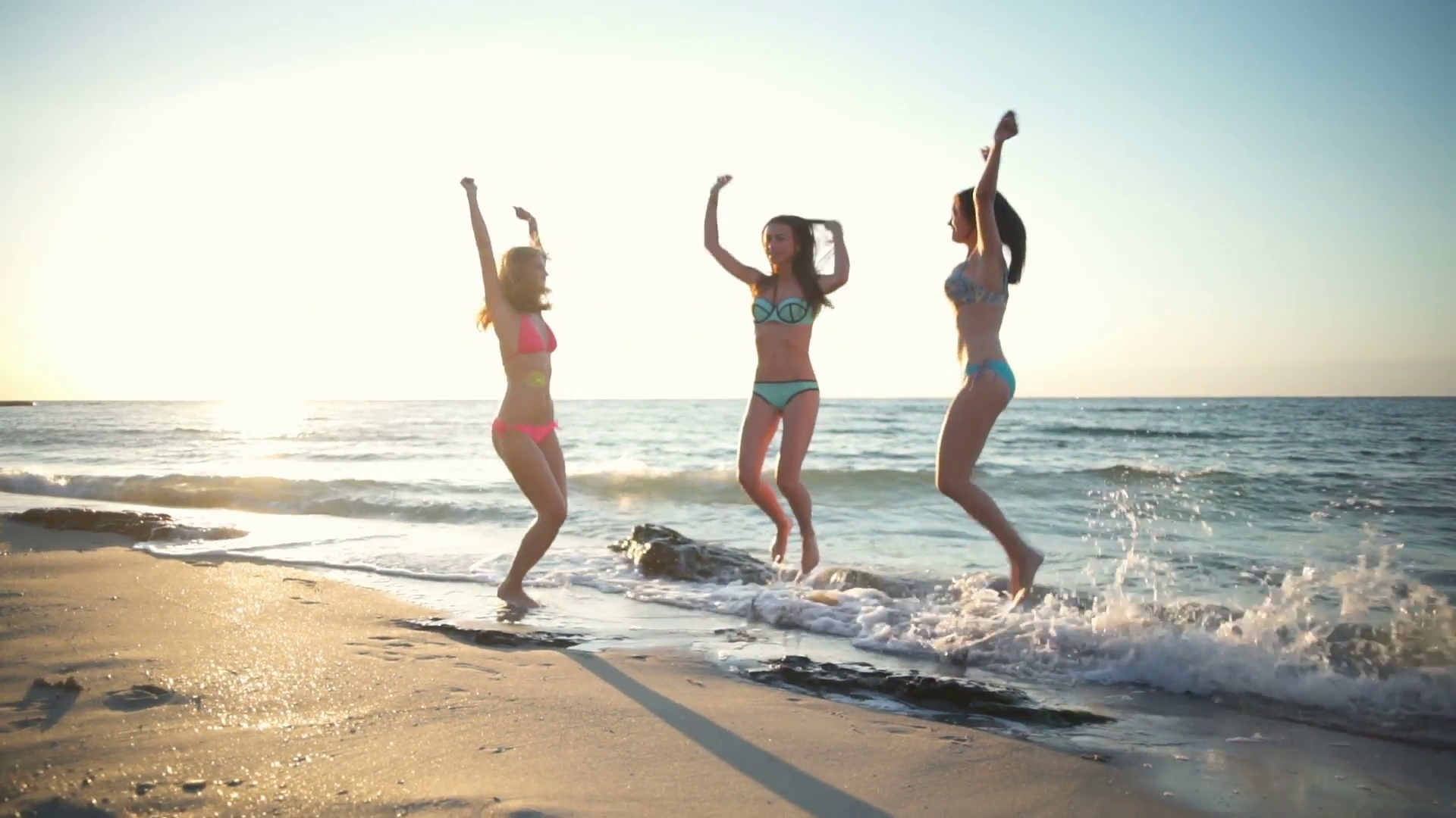 three young happy girls jumping up and down at sea side slow motion ...