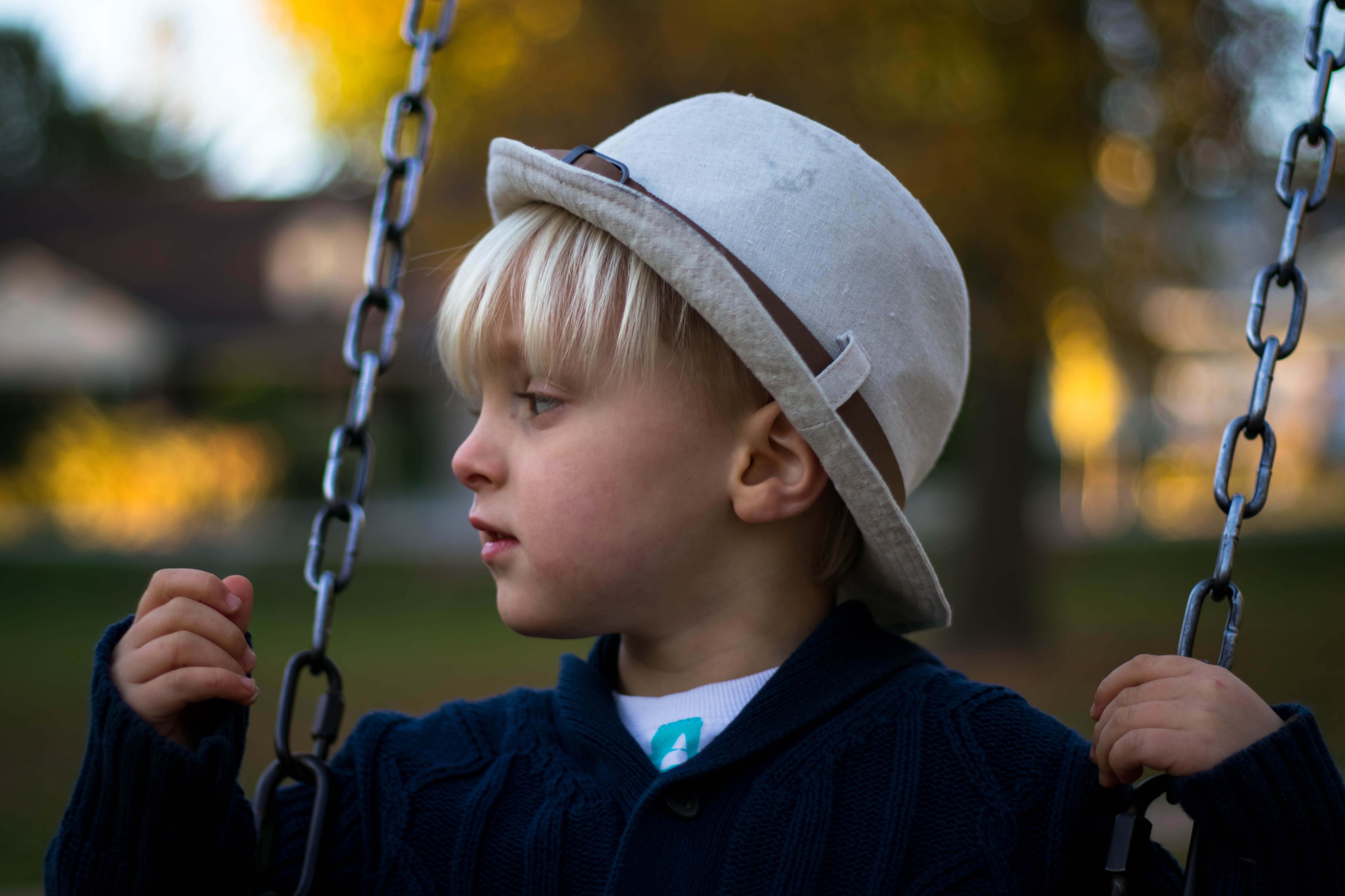 Kid in gray round hat on hanging swing photo