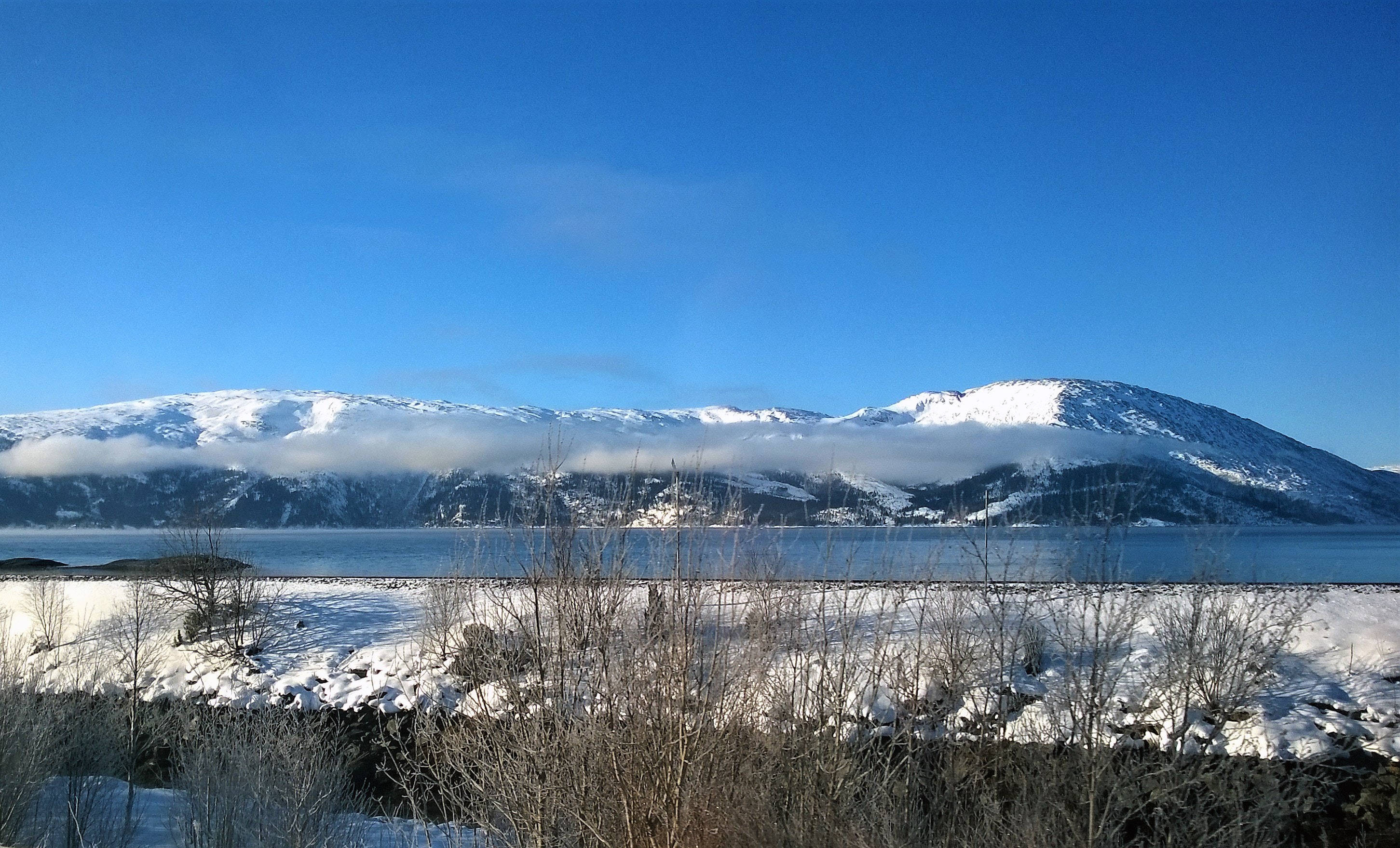 Landscape photo of body of water within snow coated mountain range