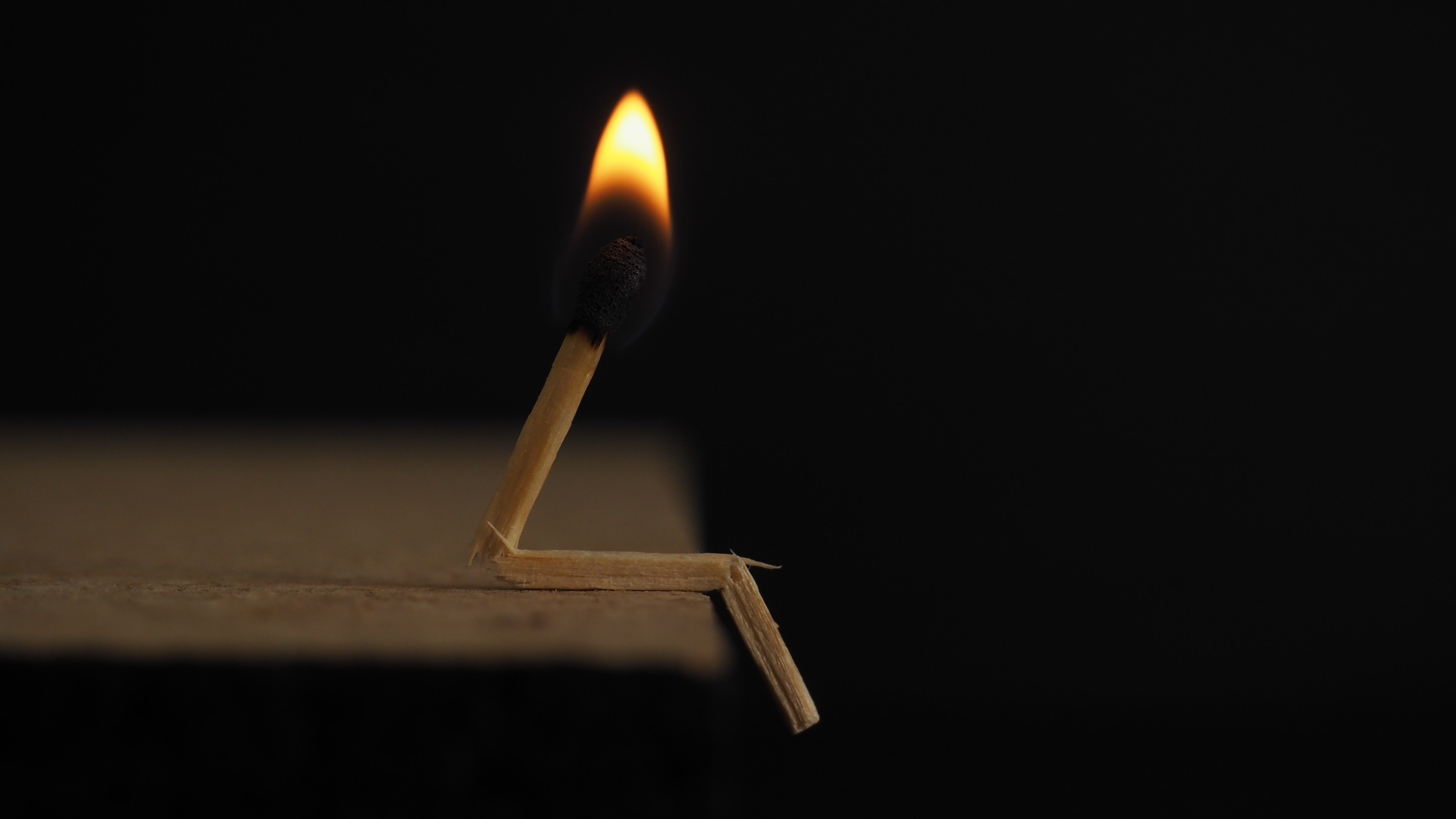 Lighted matchstick on brown wooden surface photo