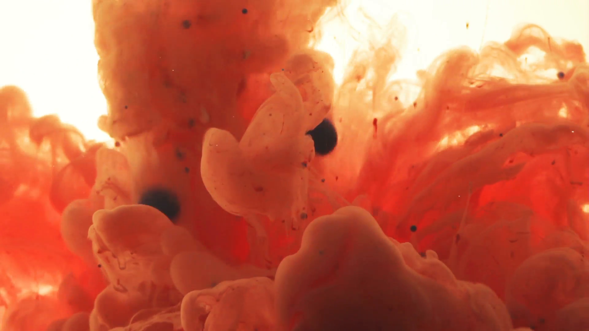 Liquid colors,yellow and red, mix underwater into orange. Bubbles ...