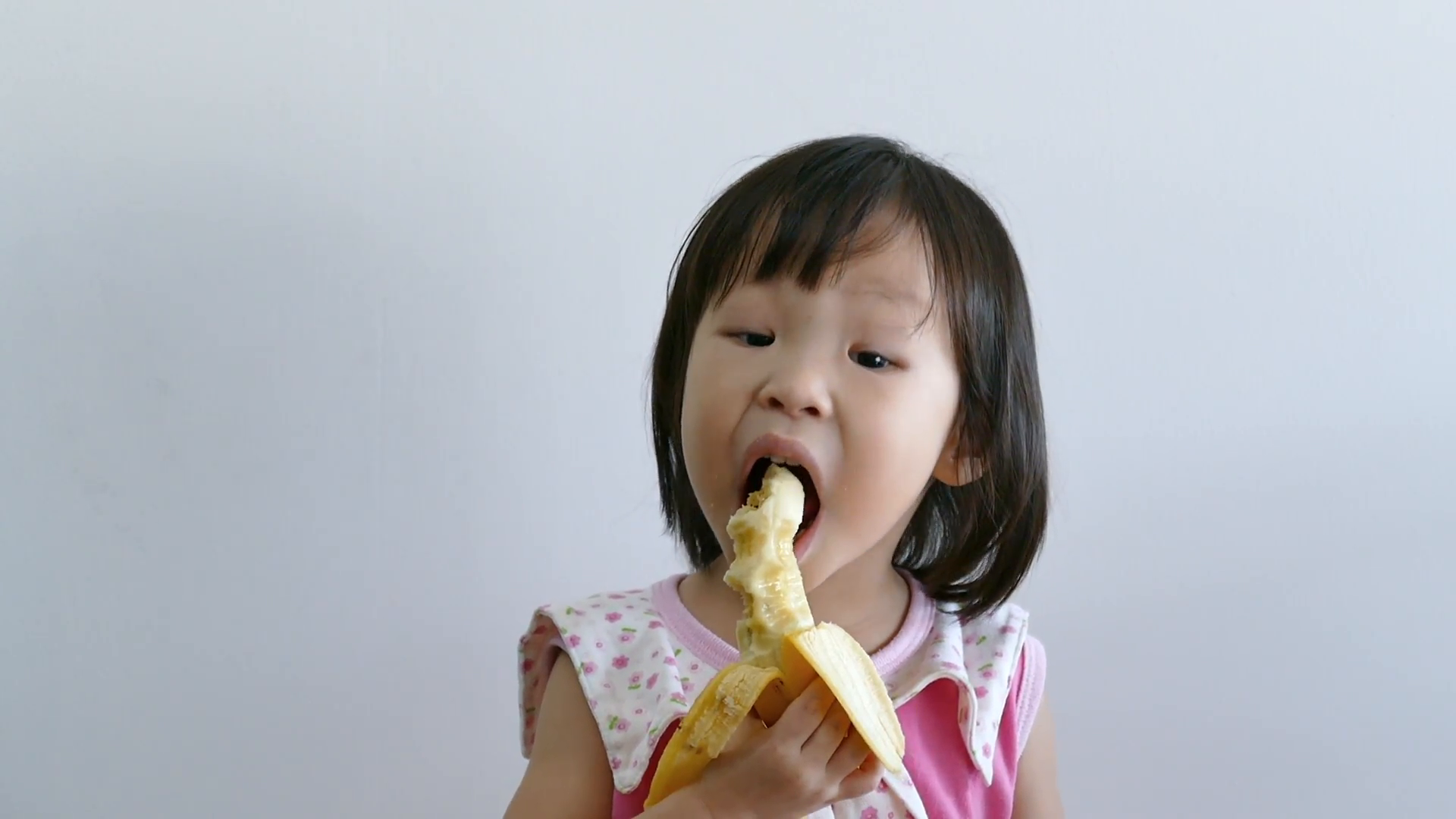 Little Asian girl eating banana Stock Video Footage - Videoblocks