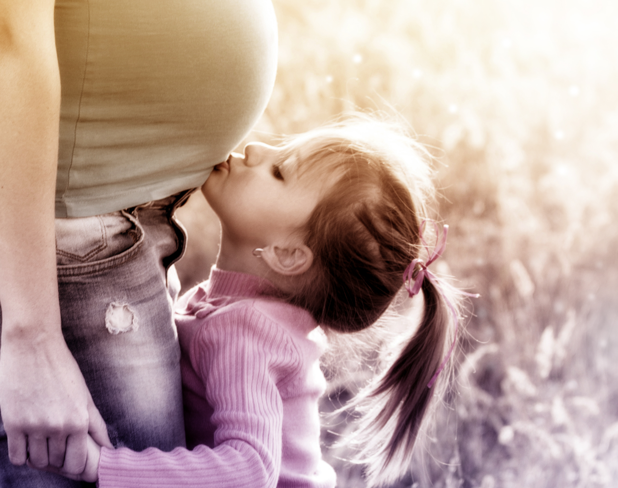 Little blonde girl kissing pregnant mother photo