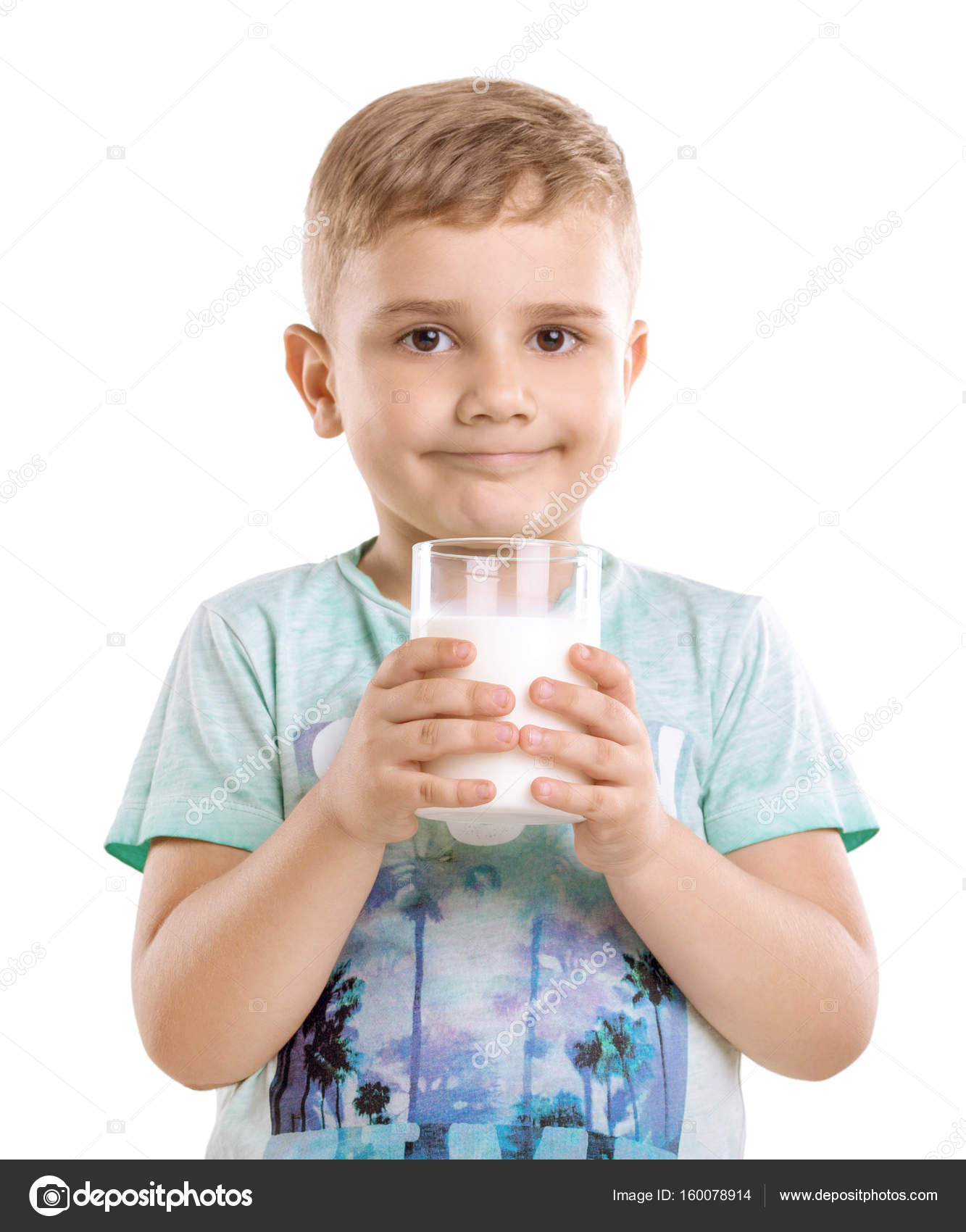 A handsome little boy holding a glass of milk in his hands isolated ...