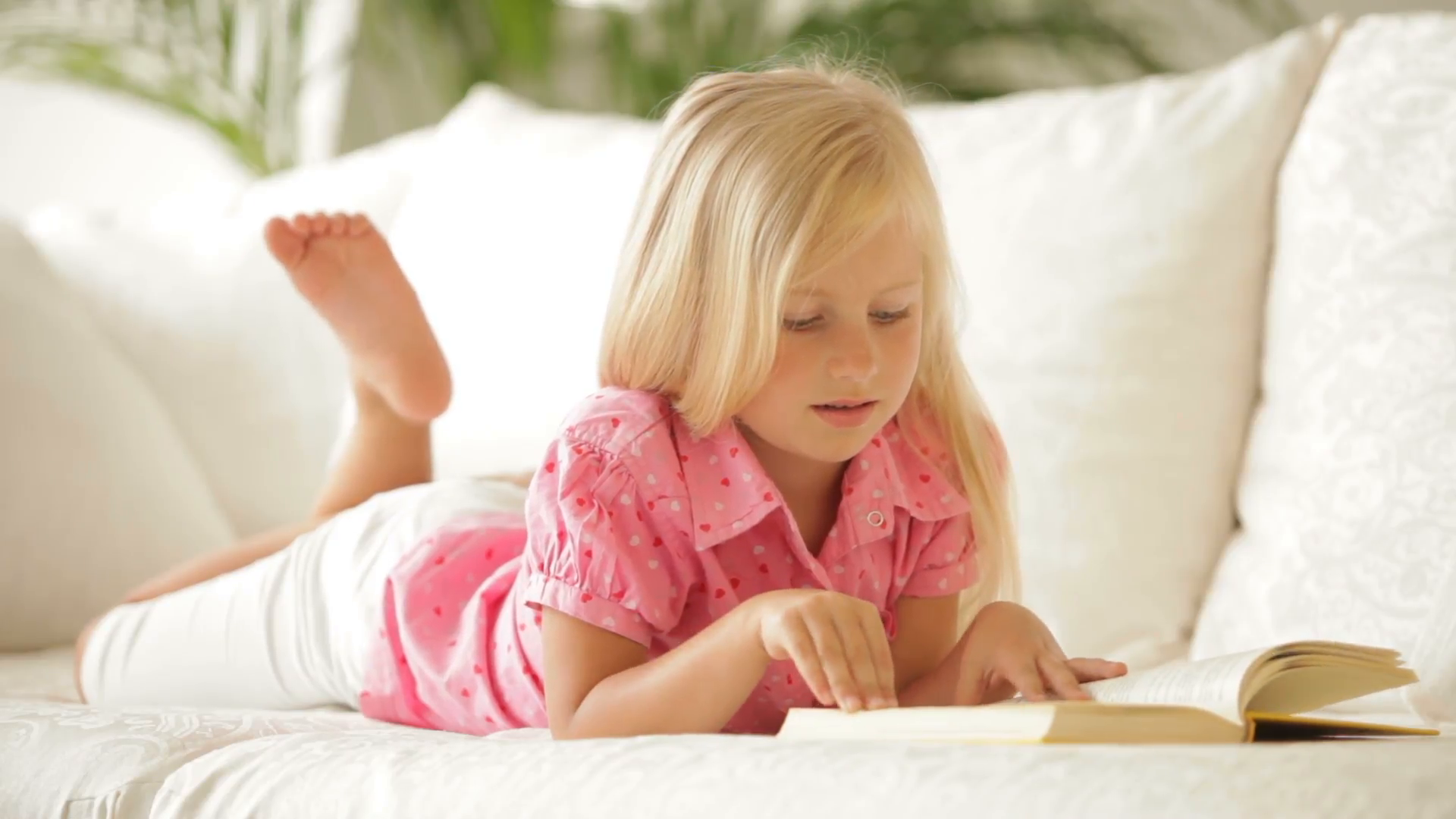 Cute little girl lying on sofa reading book and smiling Stock Video ...