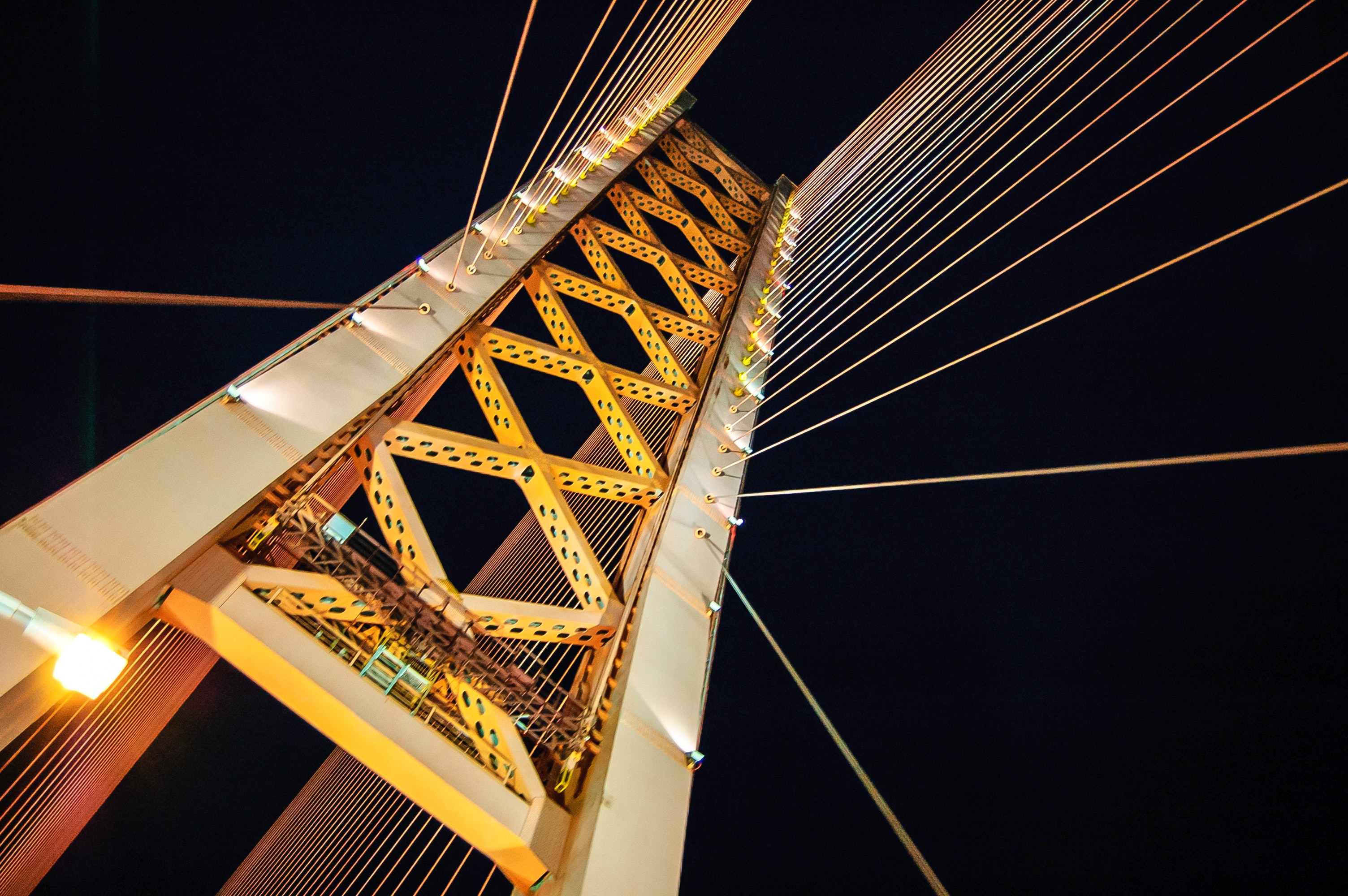 Low angle photography of white and yellow suspension bridge at nighttime