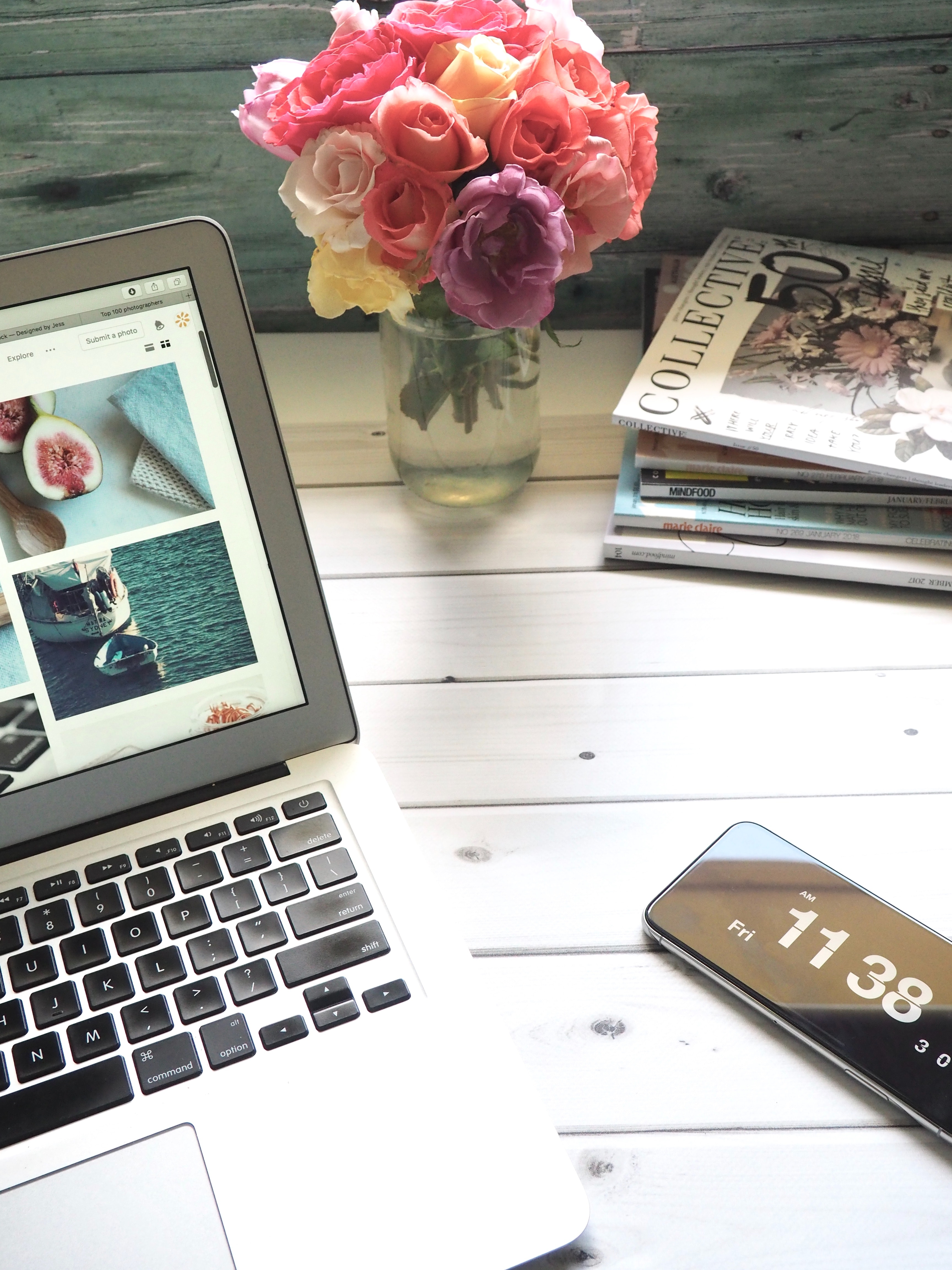 Macbook air, flower bouquet and magazines on white table photo