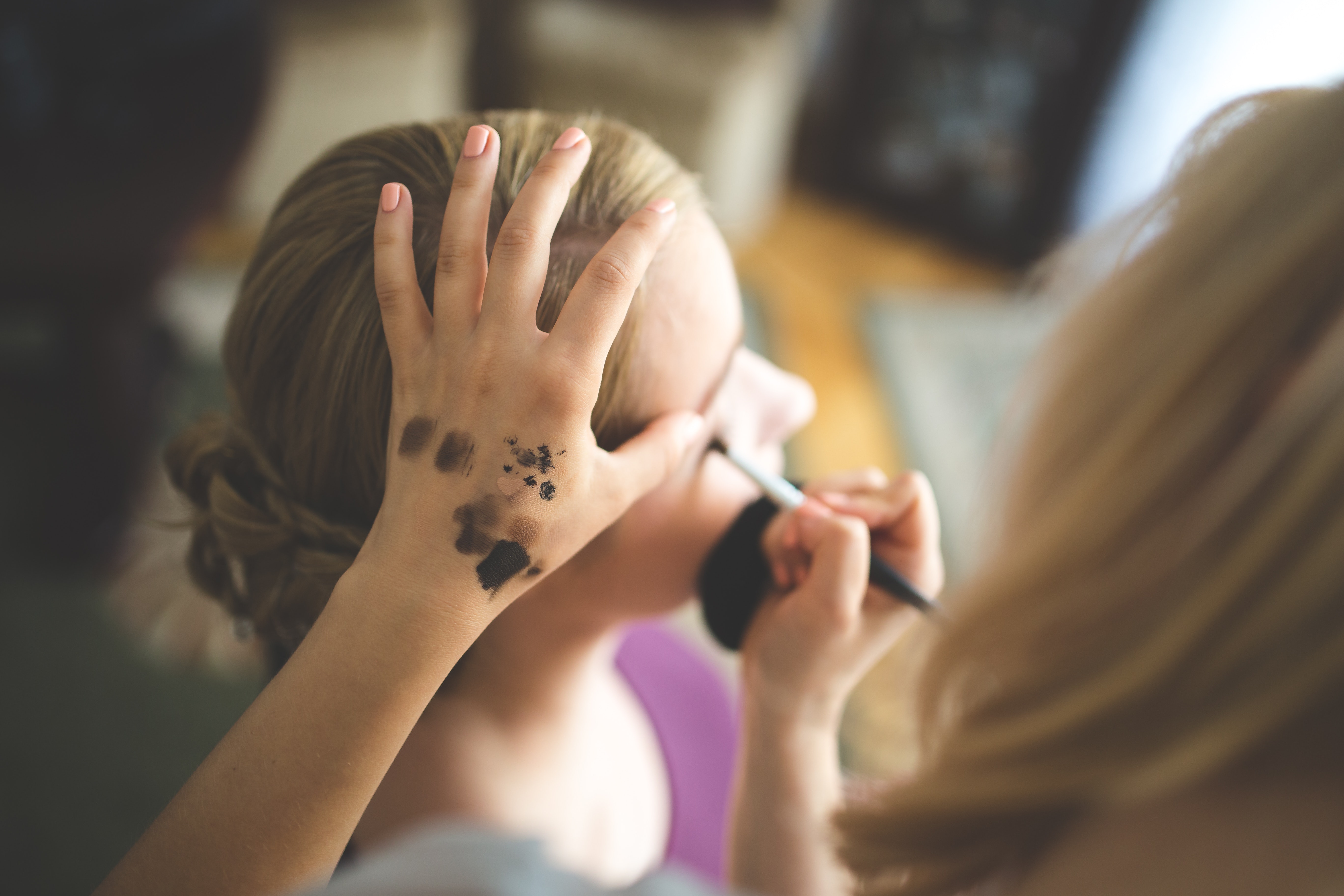 Make up artist applying shadow to a woman photo