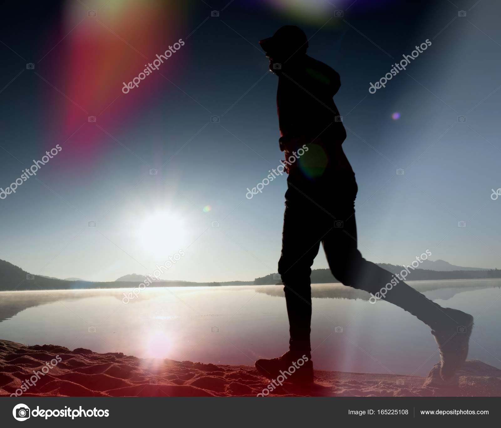 Leakage of light in the lens. Exercising man silhouette against to ...