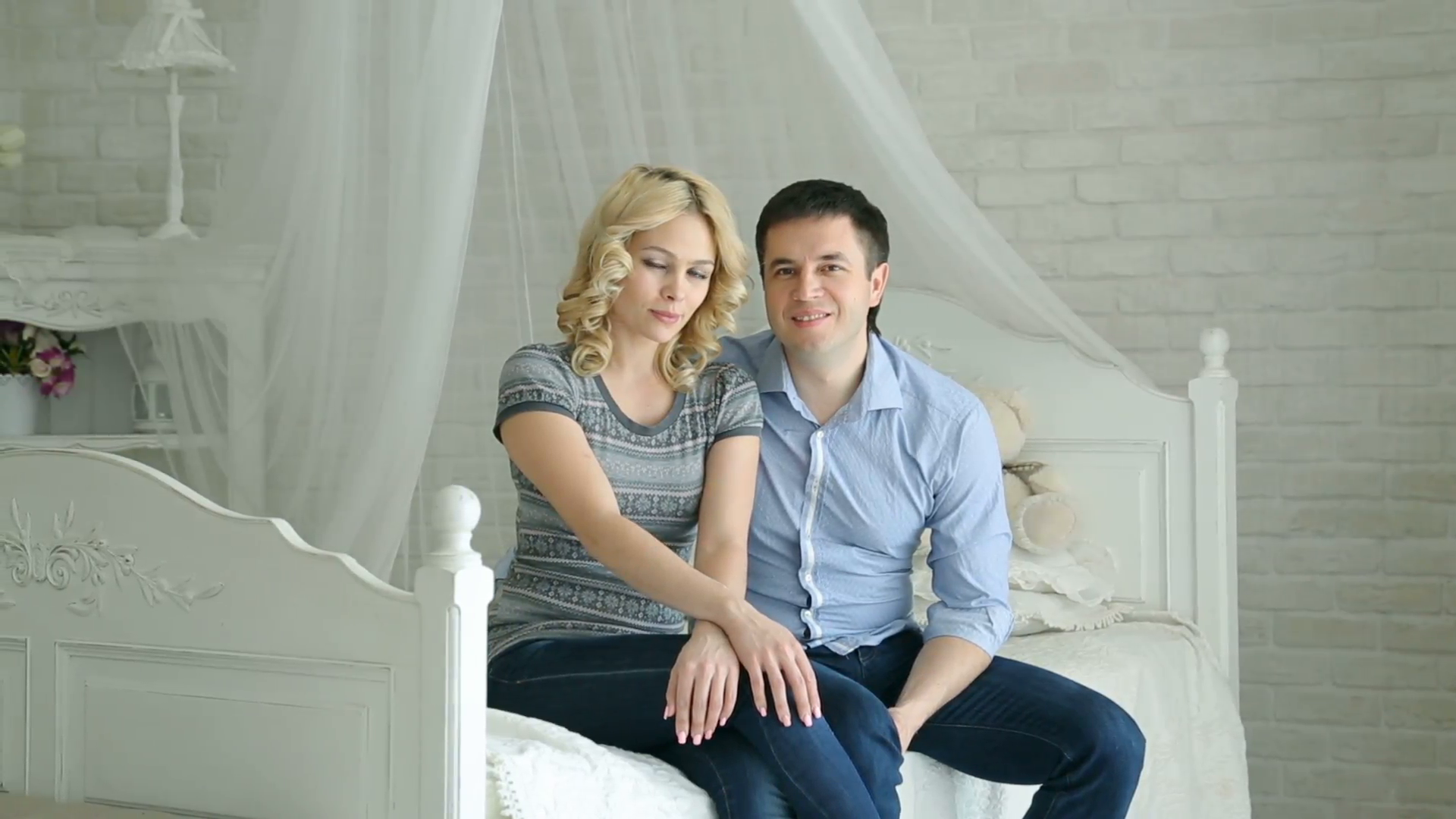 A happily married couple. Husband and wife sitting on the bed. The ...