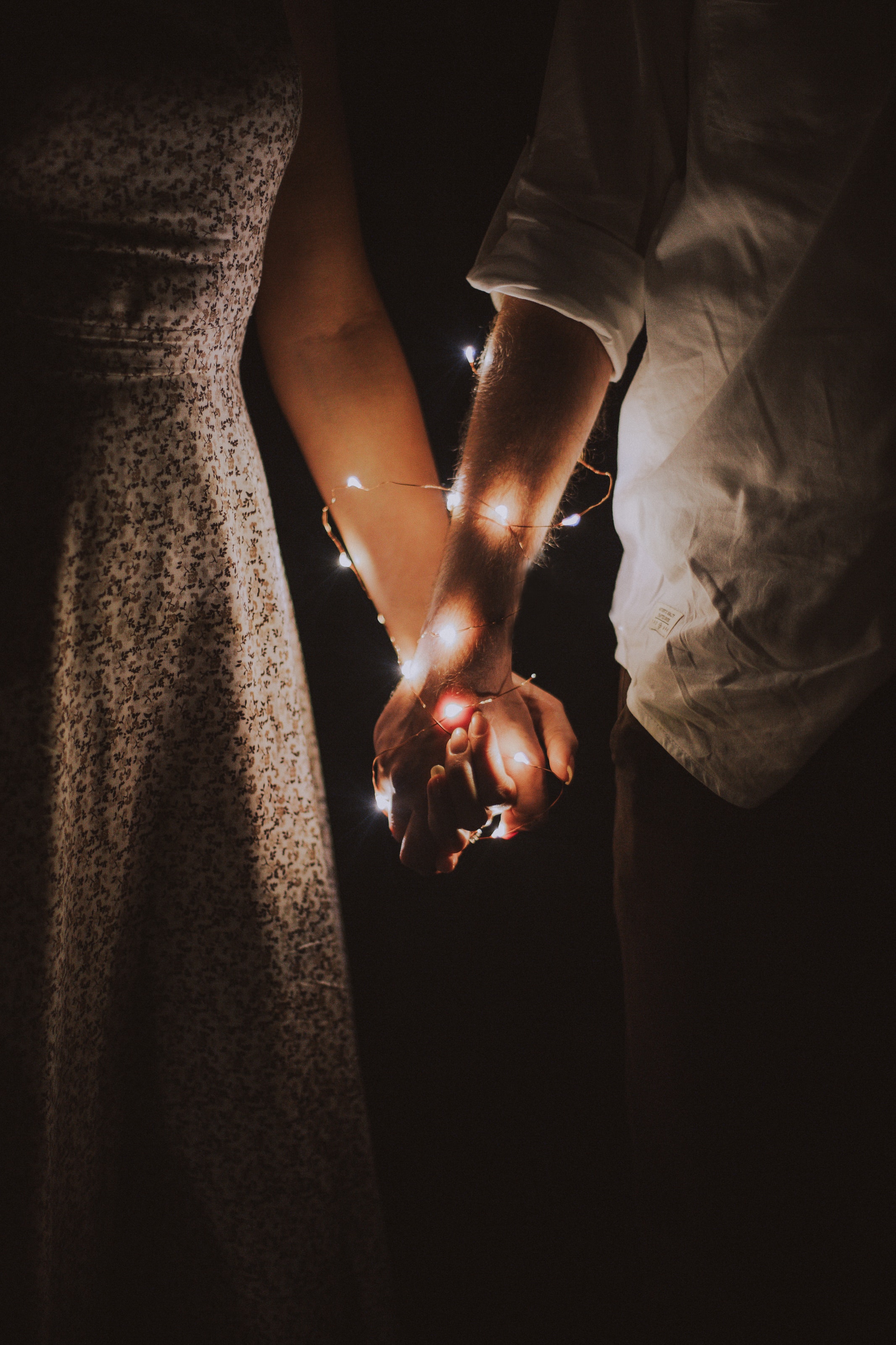 Man and woman holding each others hand wrapped with string lights photo