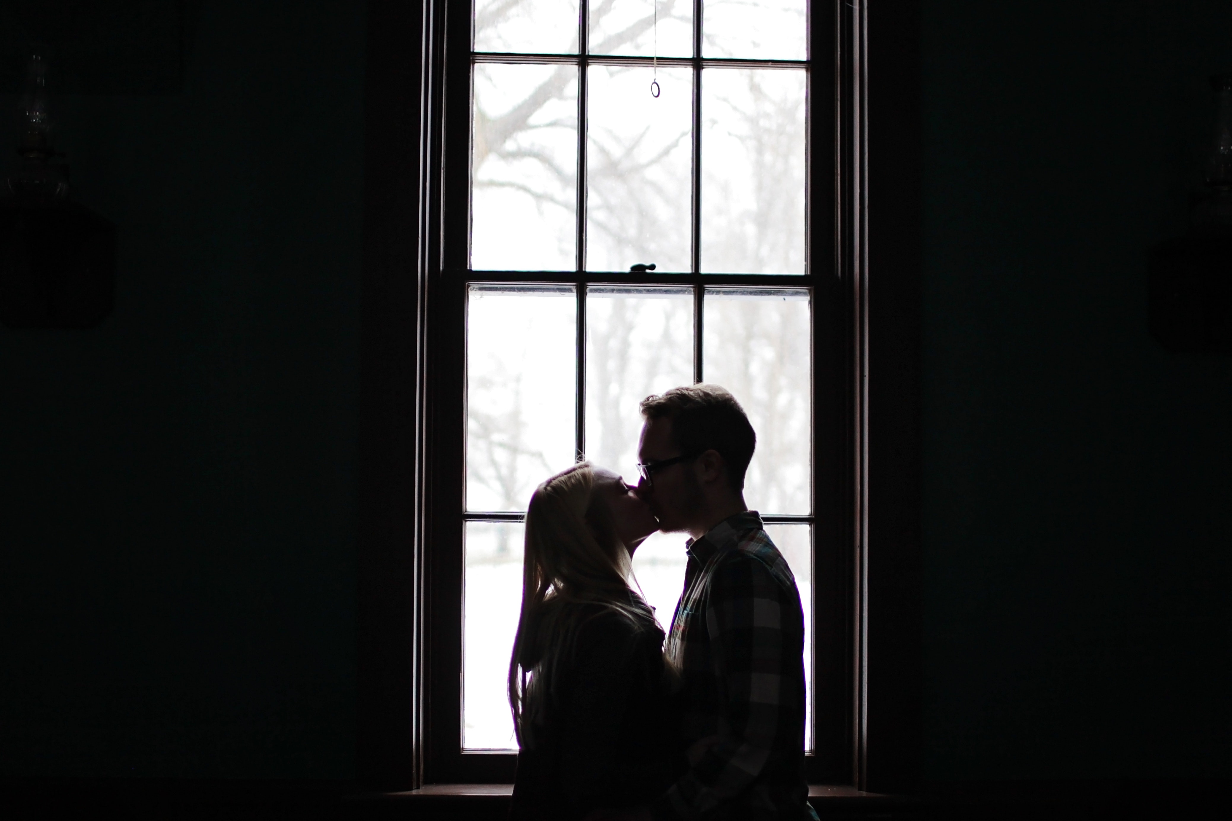 Man and woman kissing beside window photo