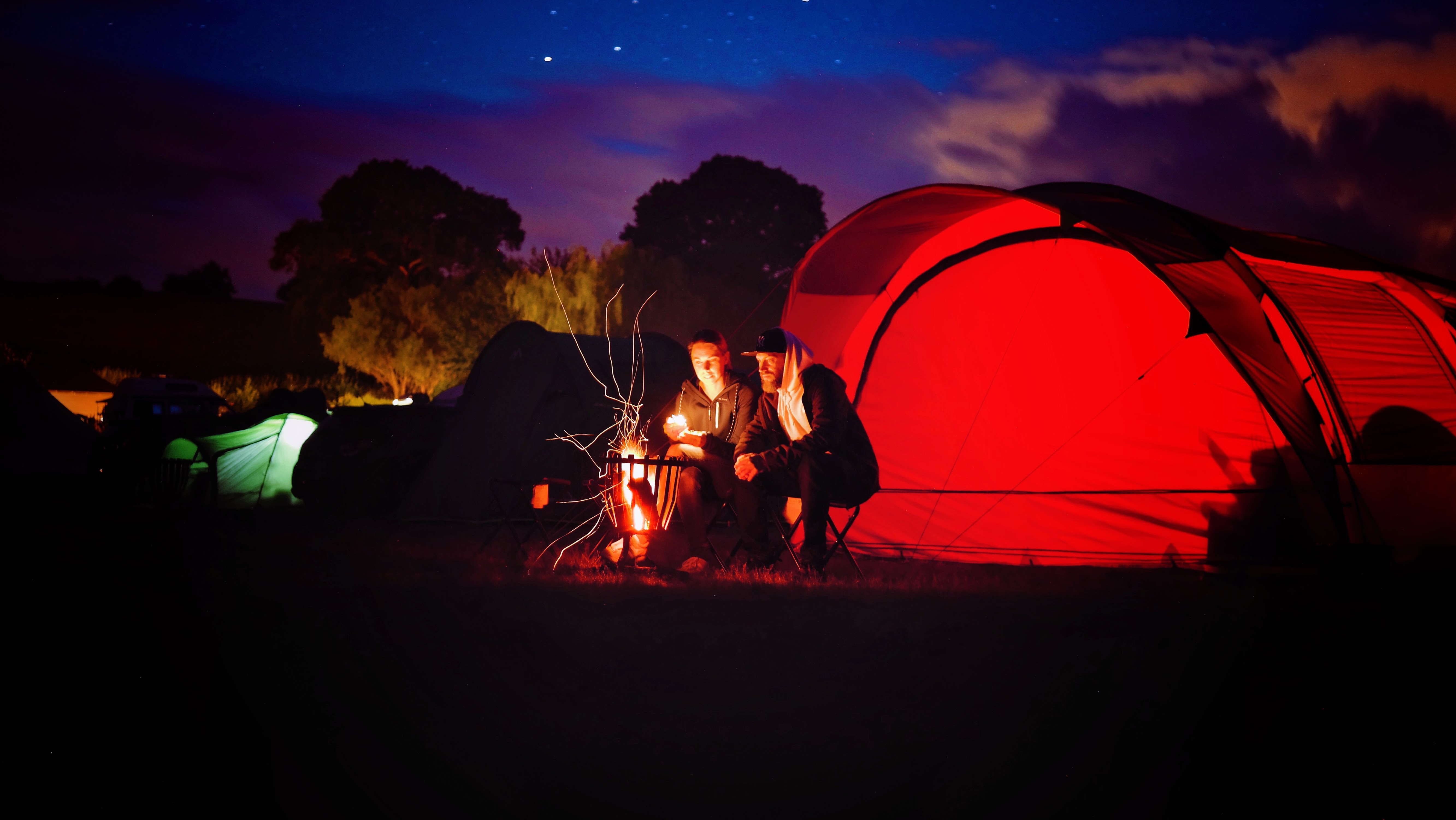 Man and woman sitting beside bonfire during nigh time photo