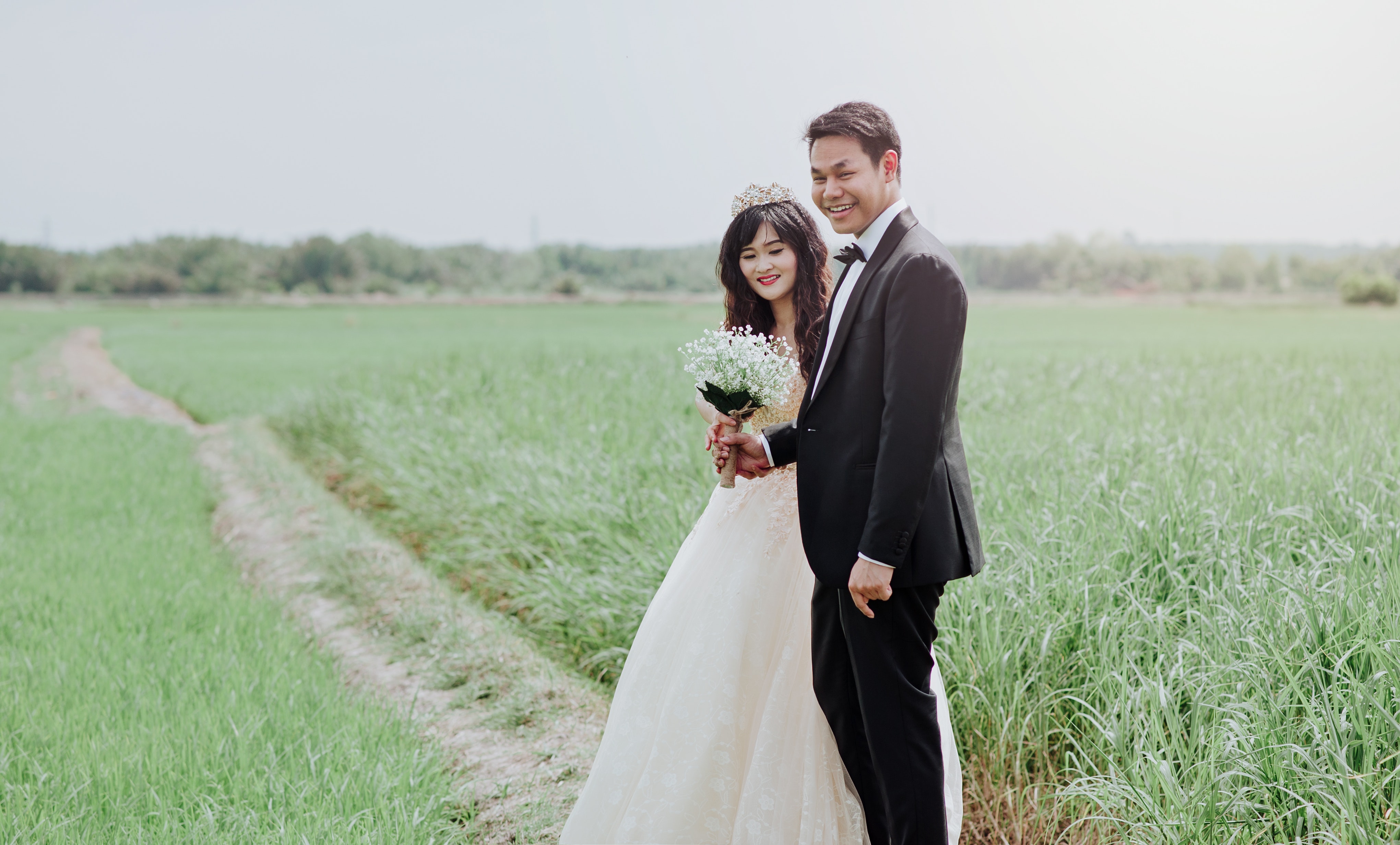 Man and woman wearing wedding dress and suit in between of rice fields photo