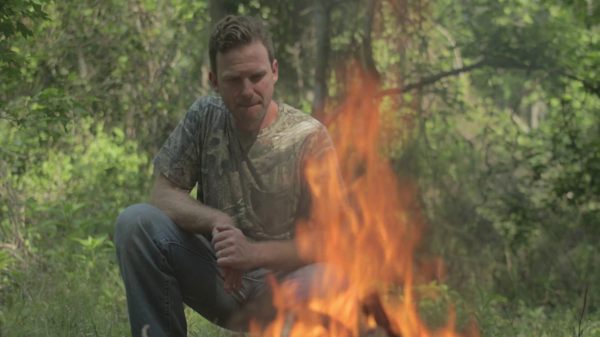 Man sits beside campfire in the forest Stock Video Footage - Videoblocks