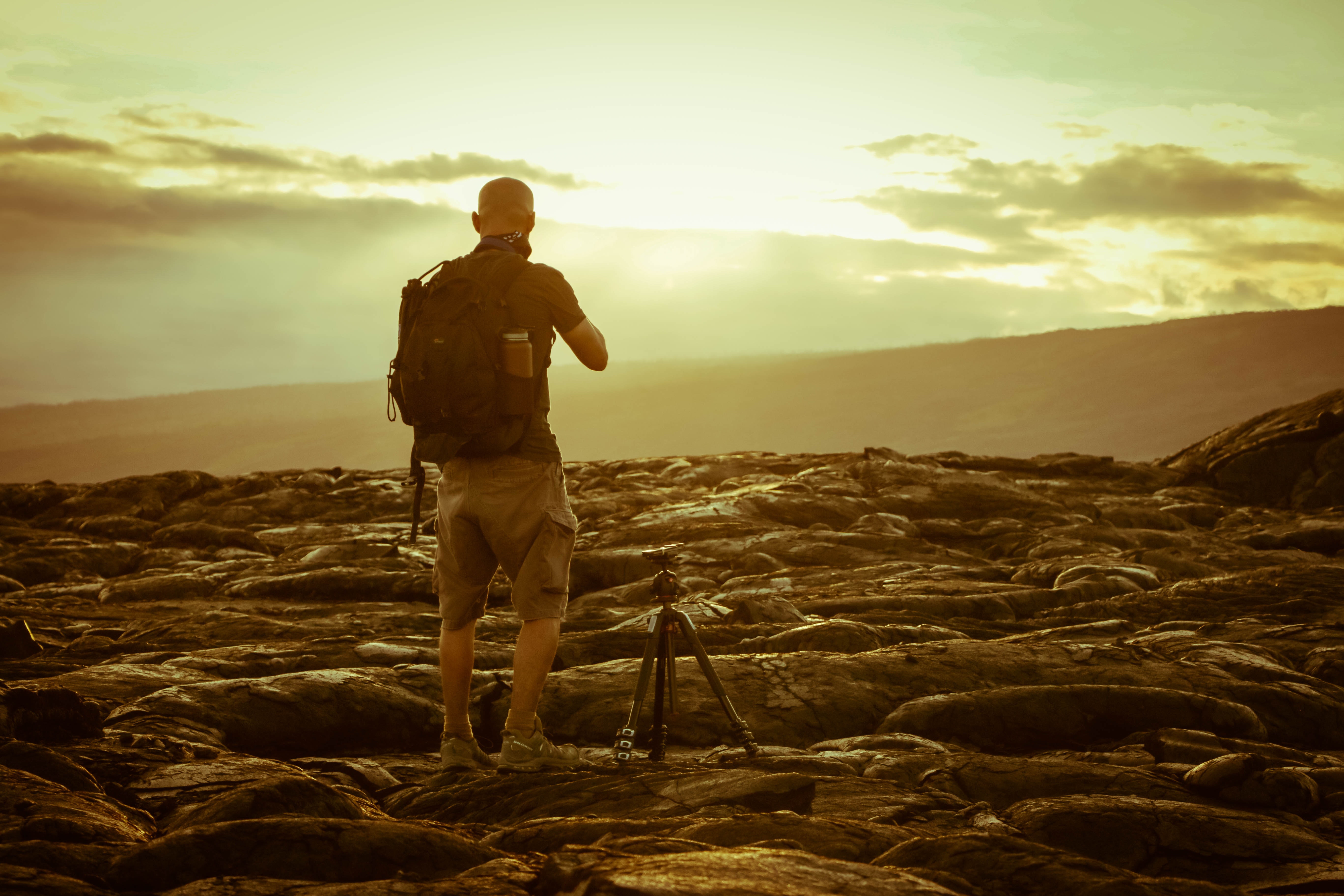 Man beside tripod on rocks during golden hour photo