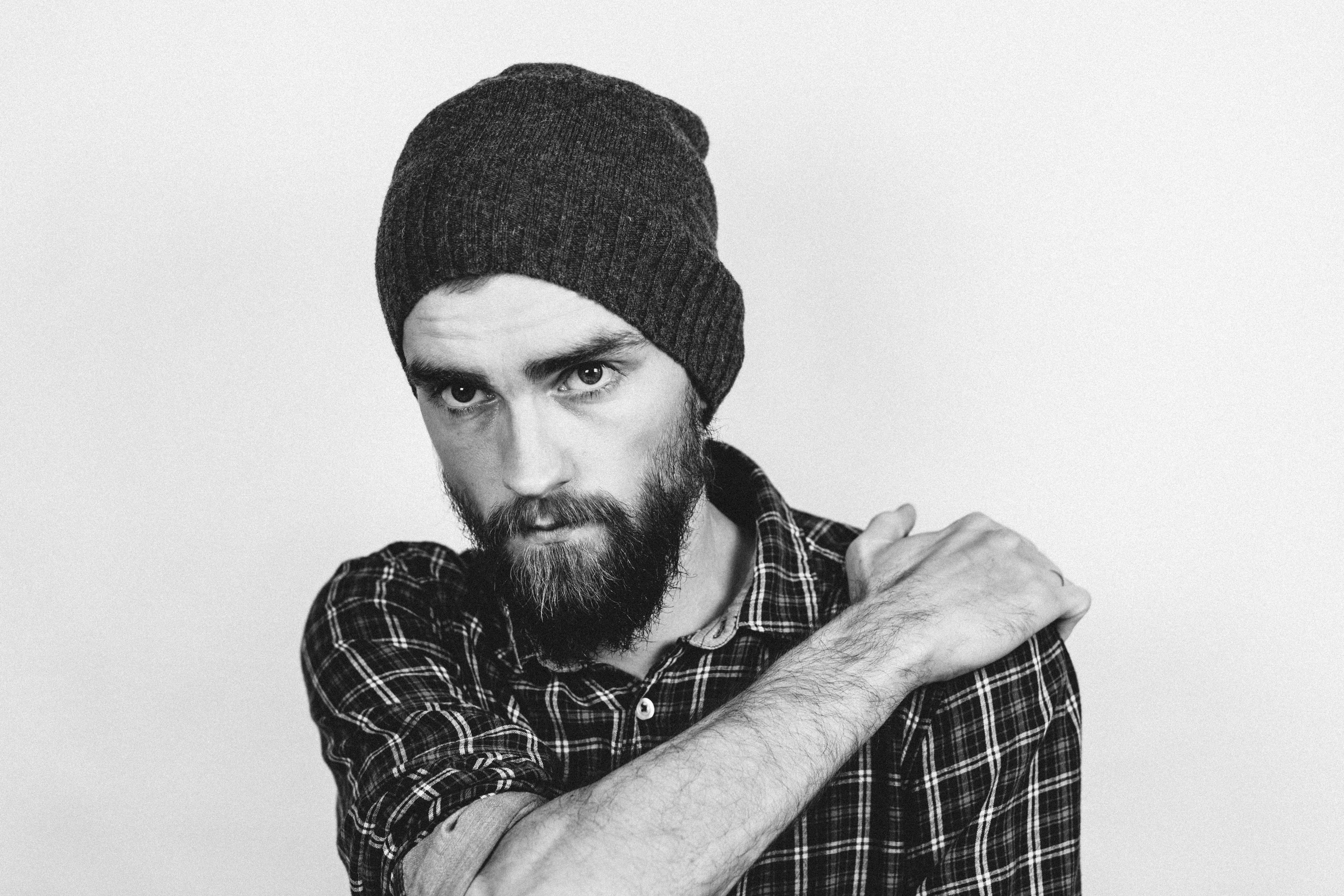 Man in beanie holding his shoulder photo