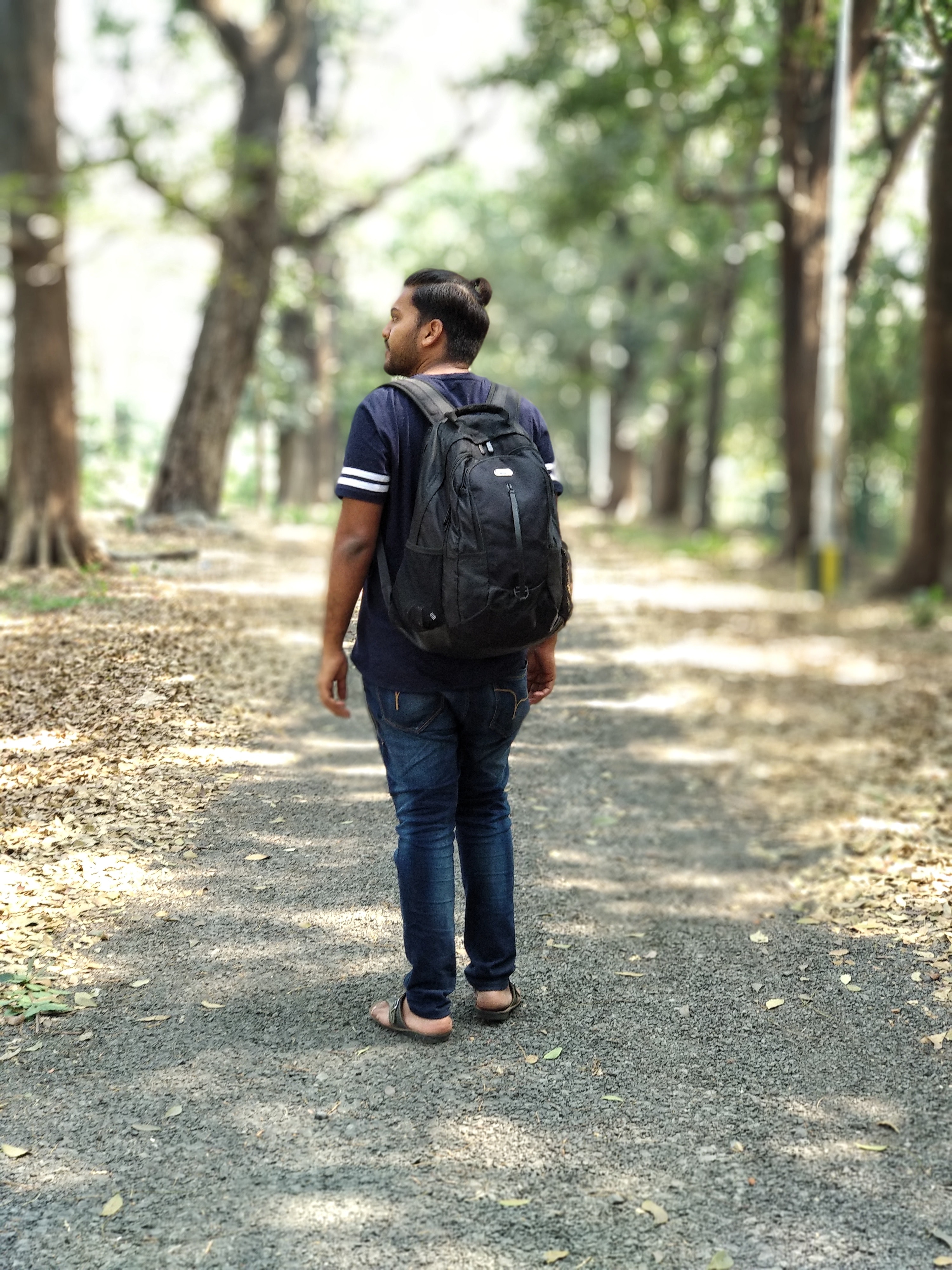 Man in black and white t-shirt and blue denim jeans carrying backpack photo