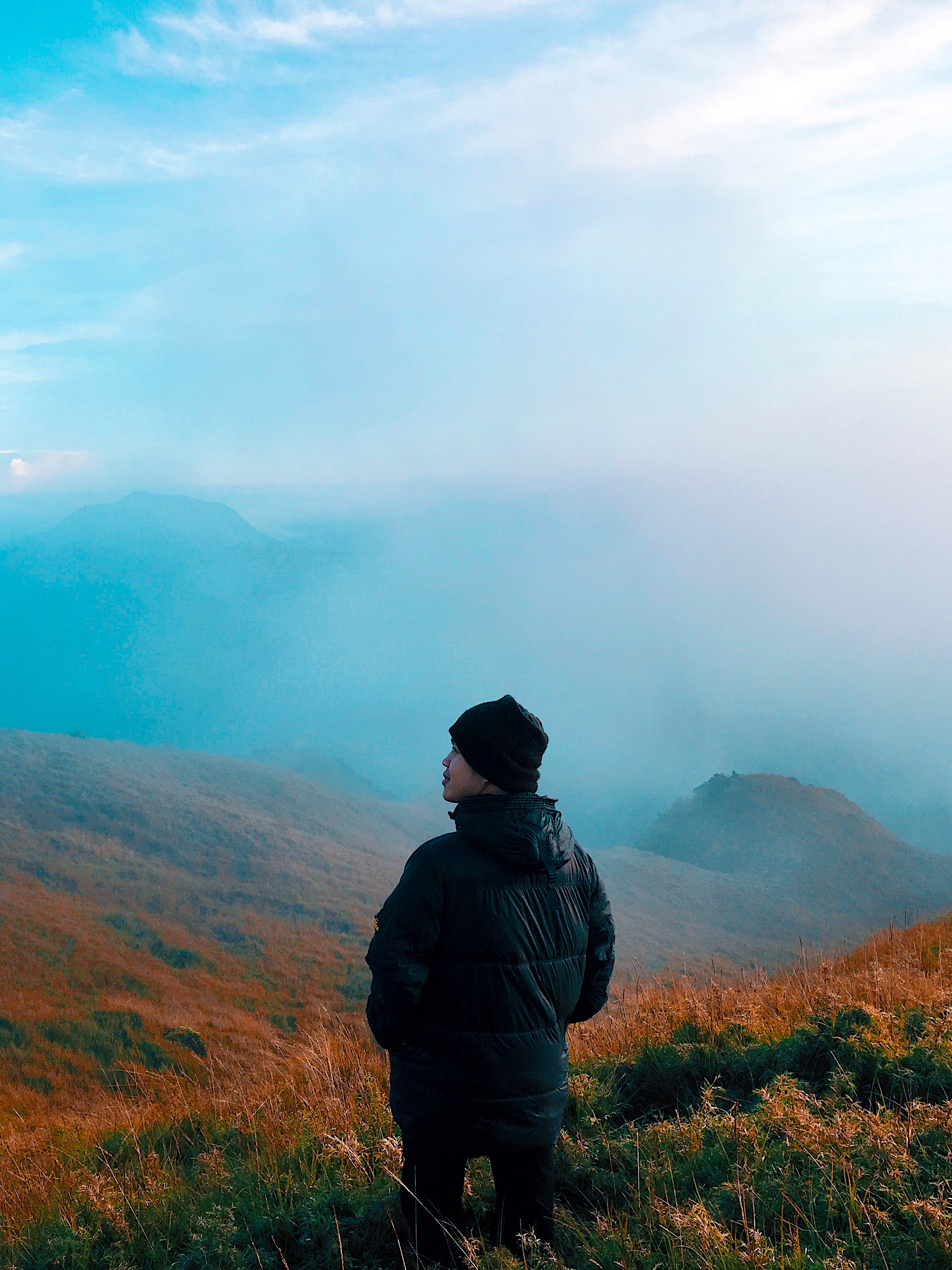 Man in black jacket standing on mountain with fog photo